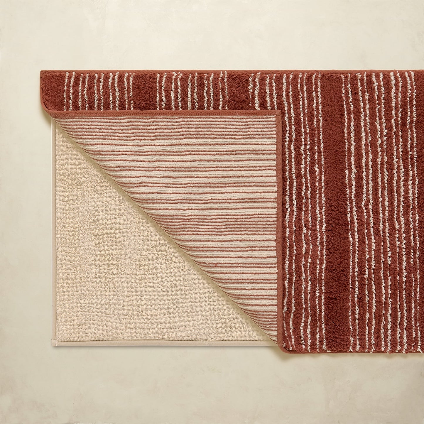 Folded rug with red and beige pattern on a neutral background