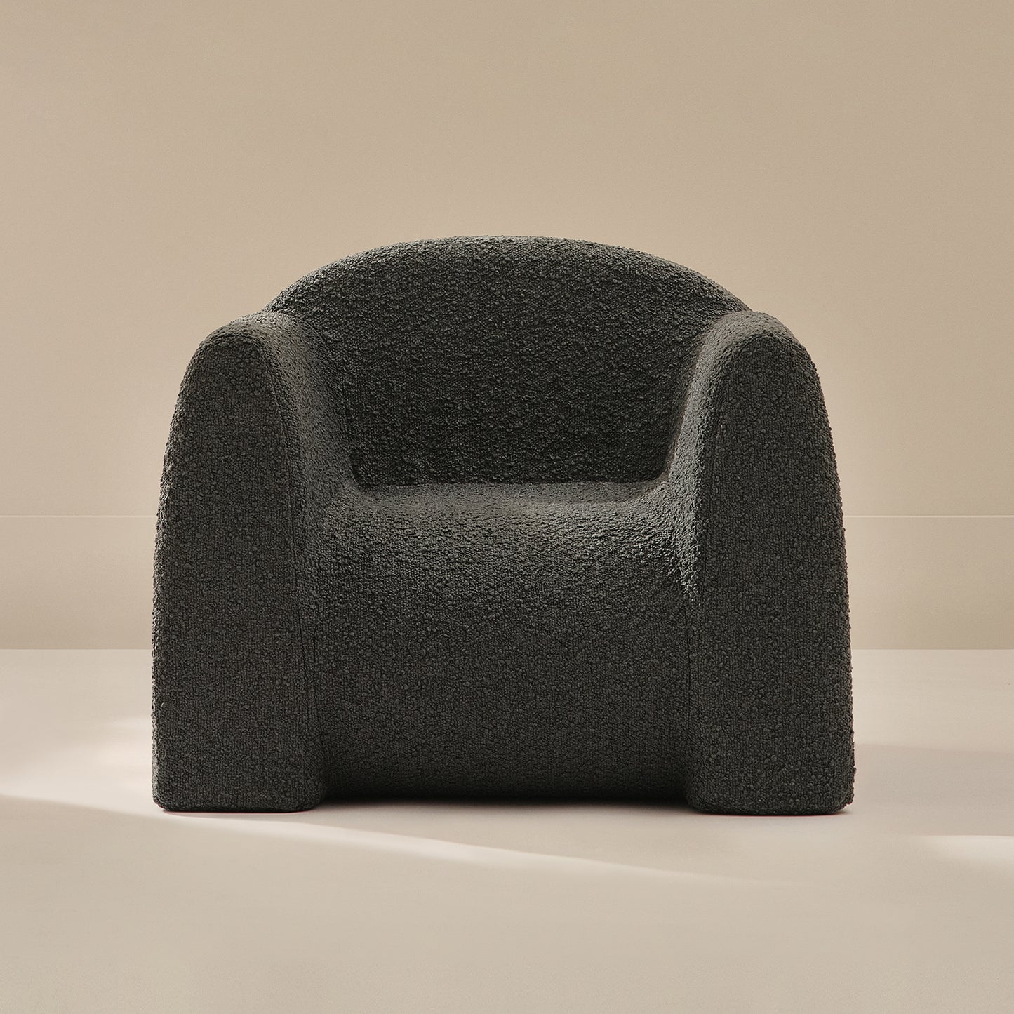 Dark gray boucle armchair on a beige background