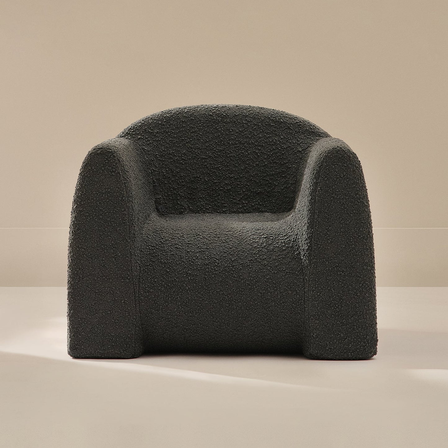 Dark gray boucle armchair on a beige background