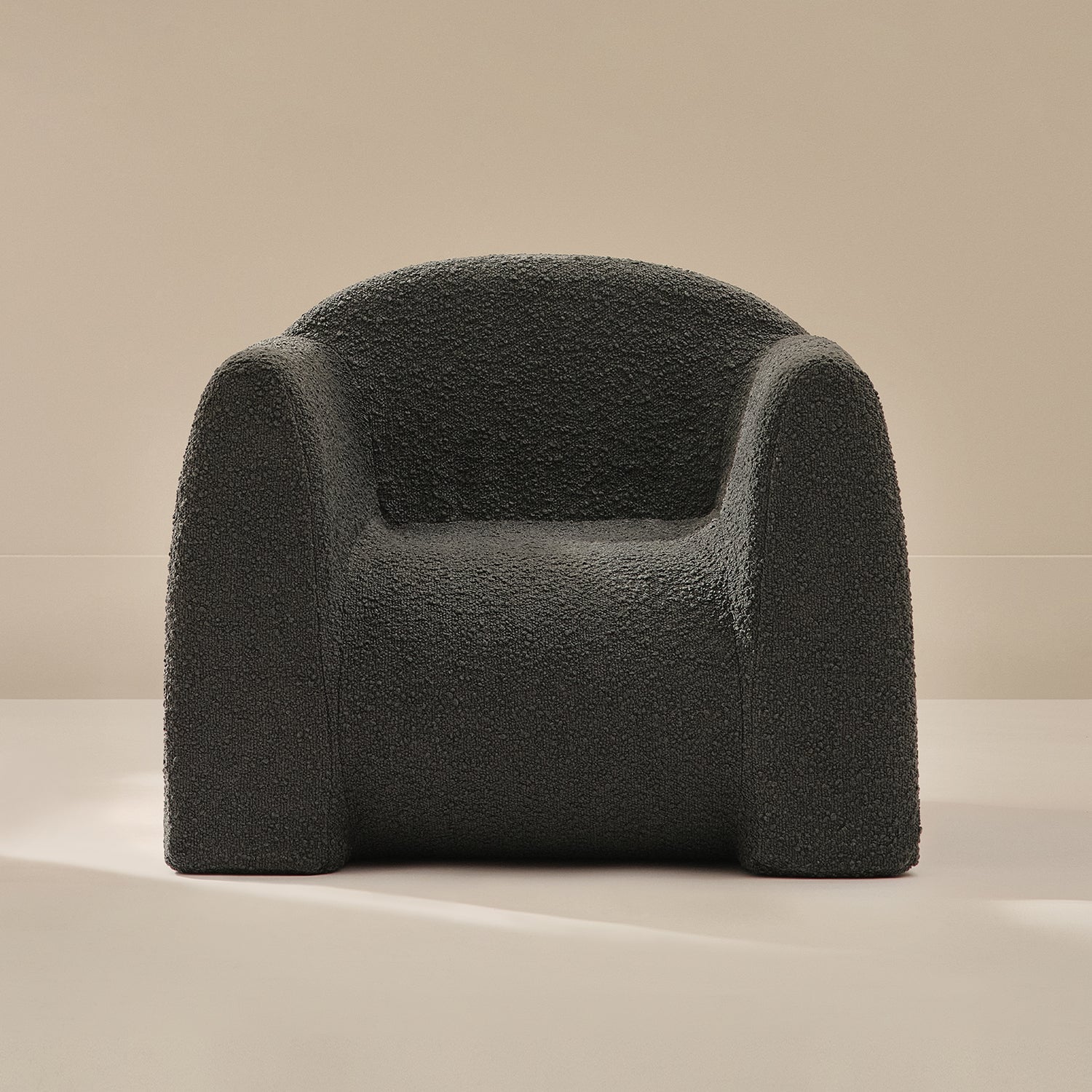 Dark gray boucle armchair on a beige background