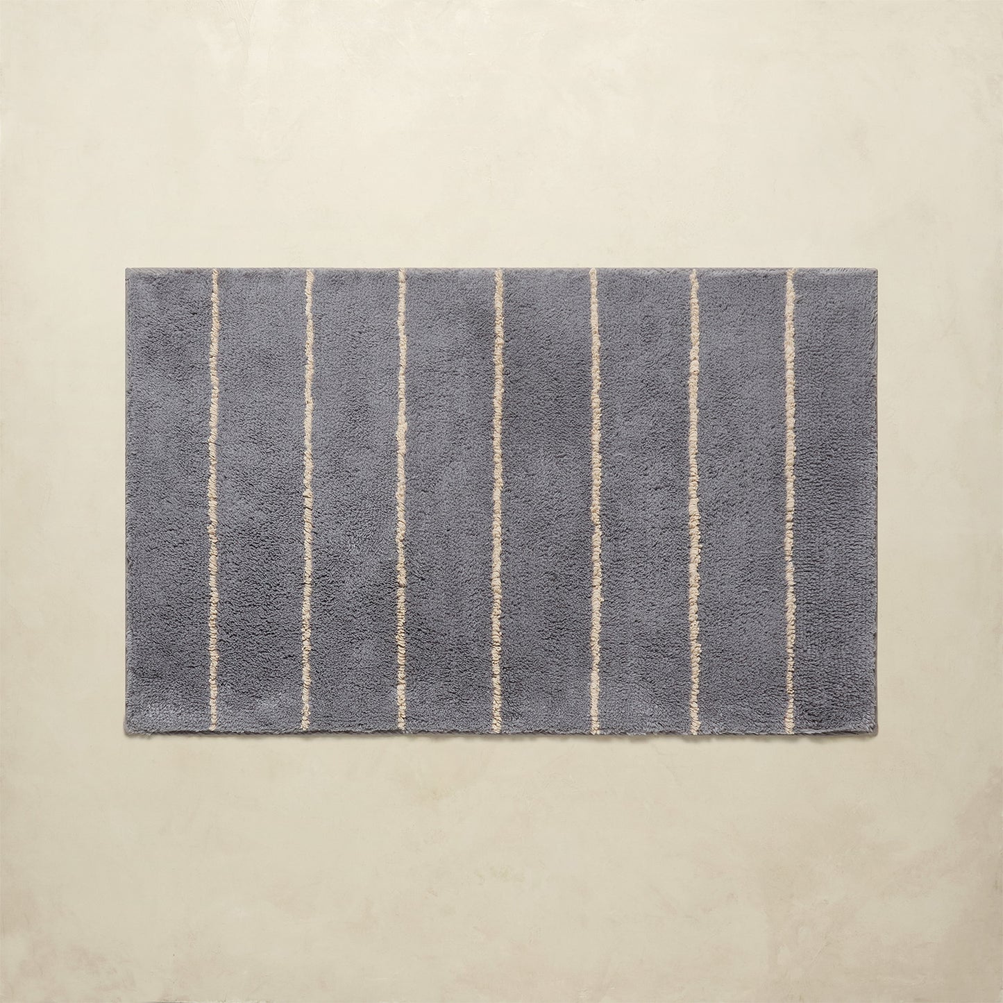 Rectangular bath mat with vertical stripes on a beige background