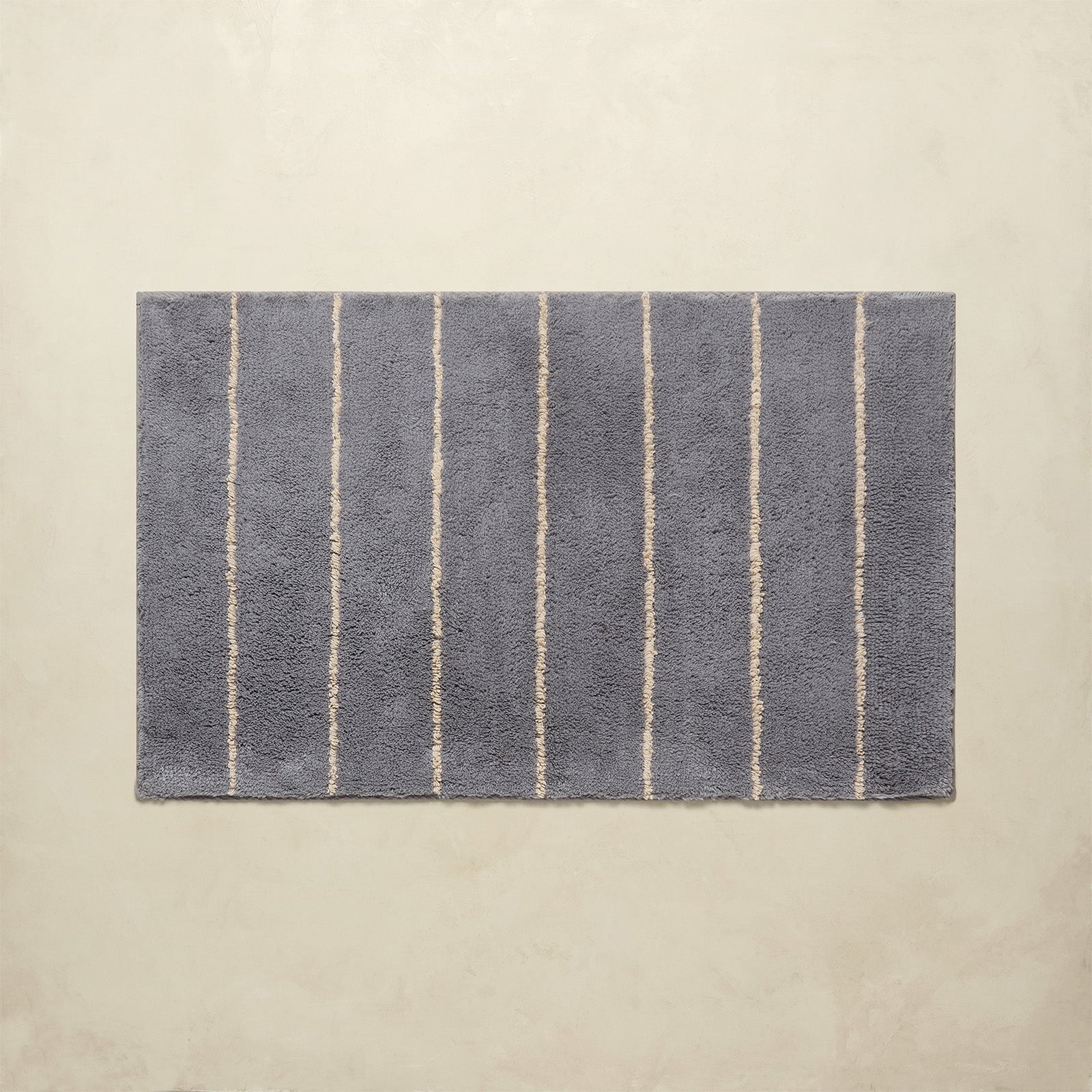 Rectangular bath mat with vertical stripes on a beige background