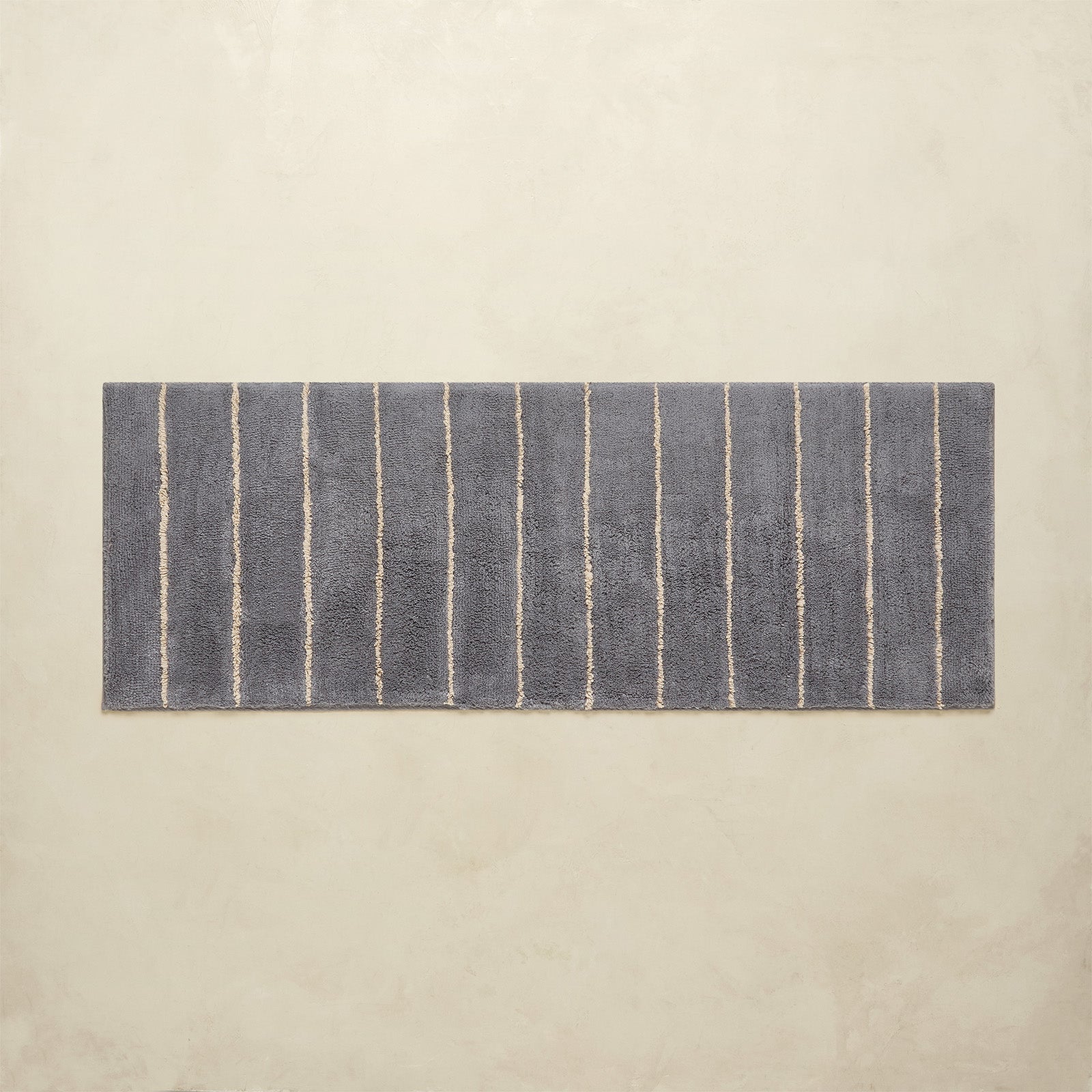 Rectangular blue and white striped bath rug on a beige background
