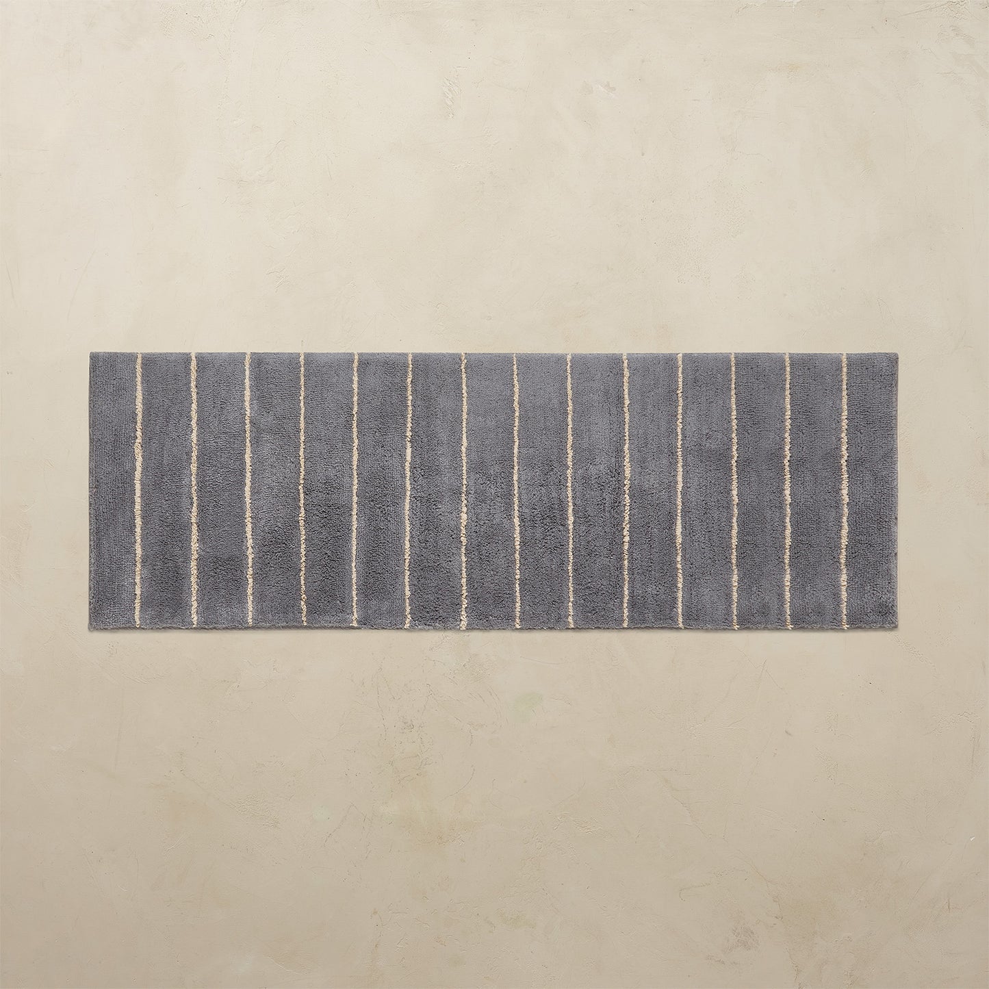 Rectangular blue bath rug with white stripes on a beige background