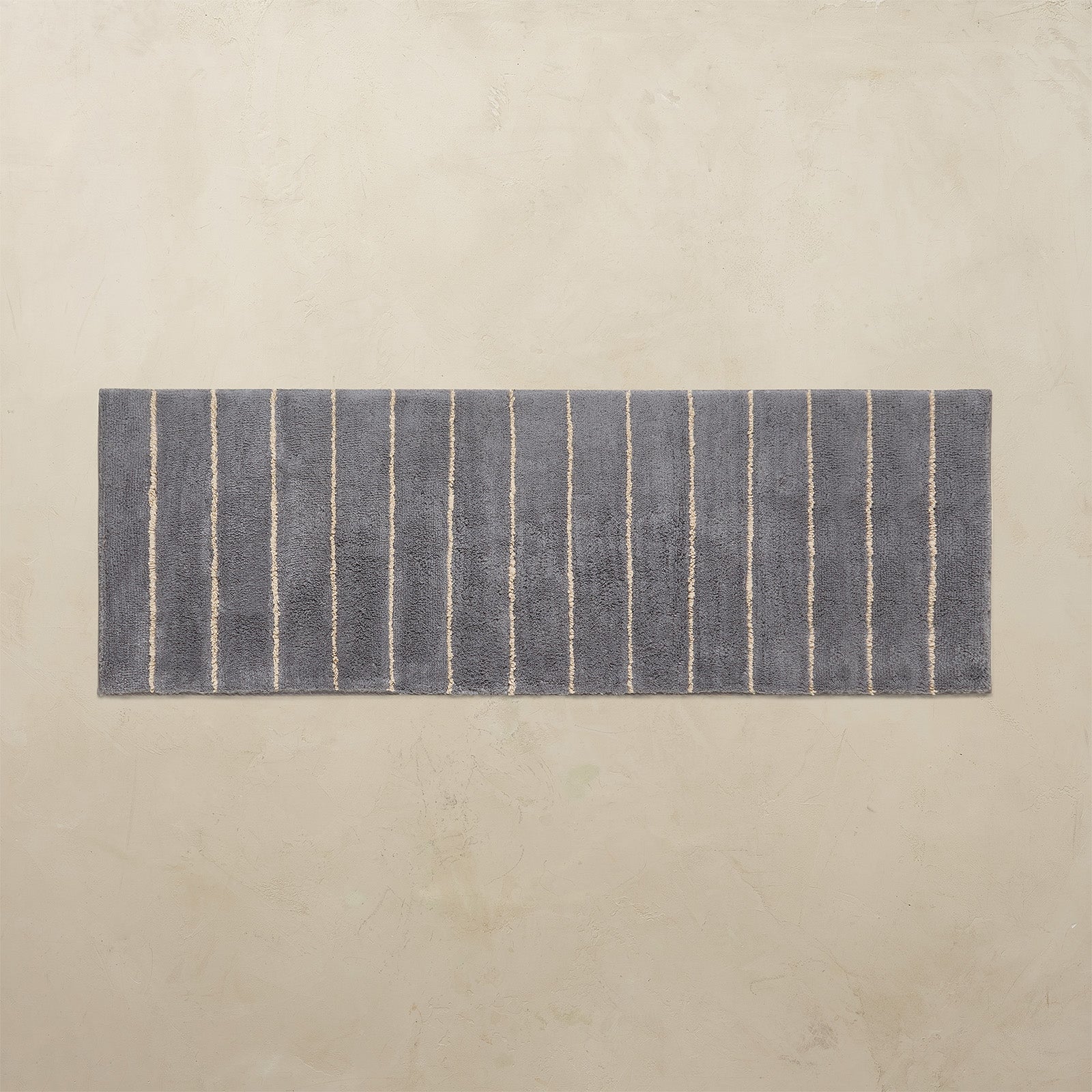 Rectangular blue bath rug with white stripes on a beige background