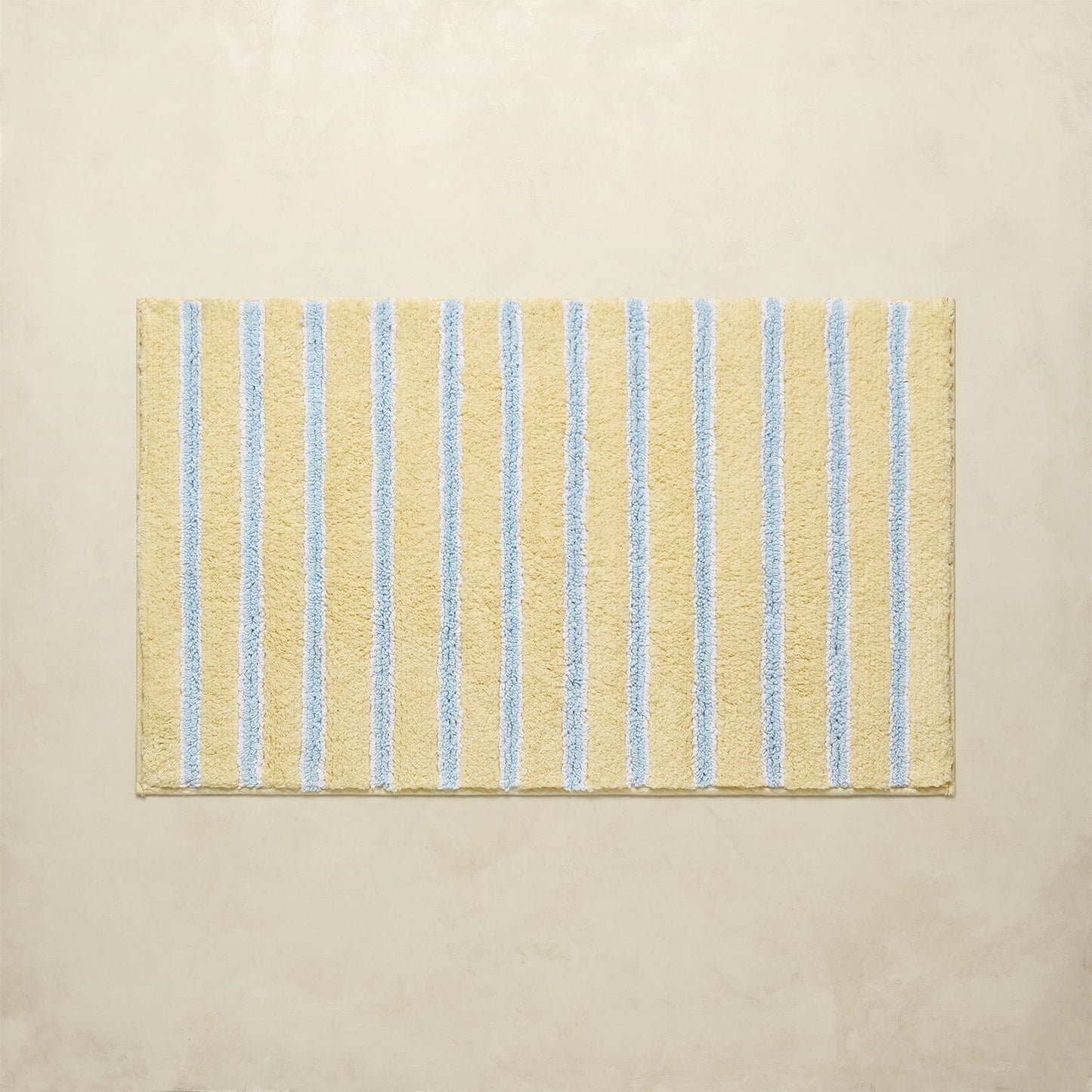 Beige bath mat with blue stripes on a beige background