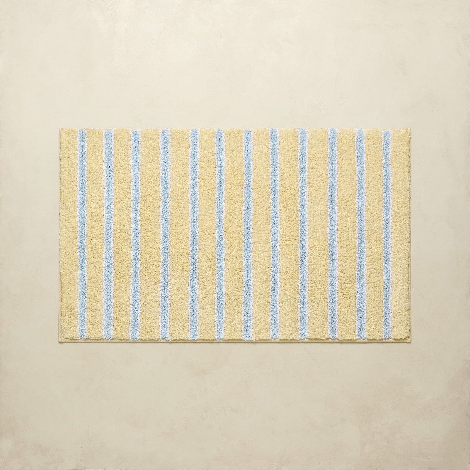 Beige bath mat with blue stripes on a beige background