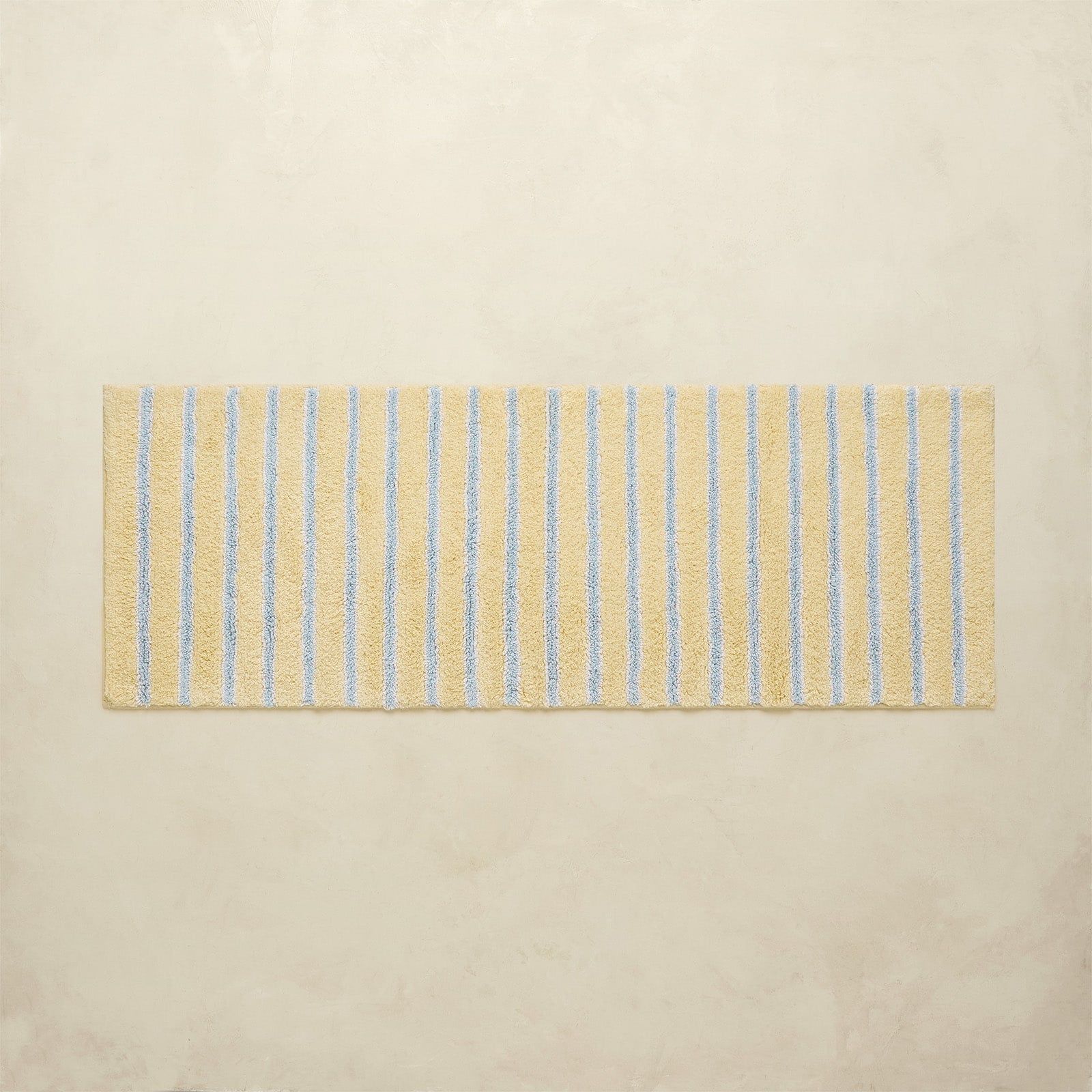 Rectangular bath mat with blue stripes on a beige background