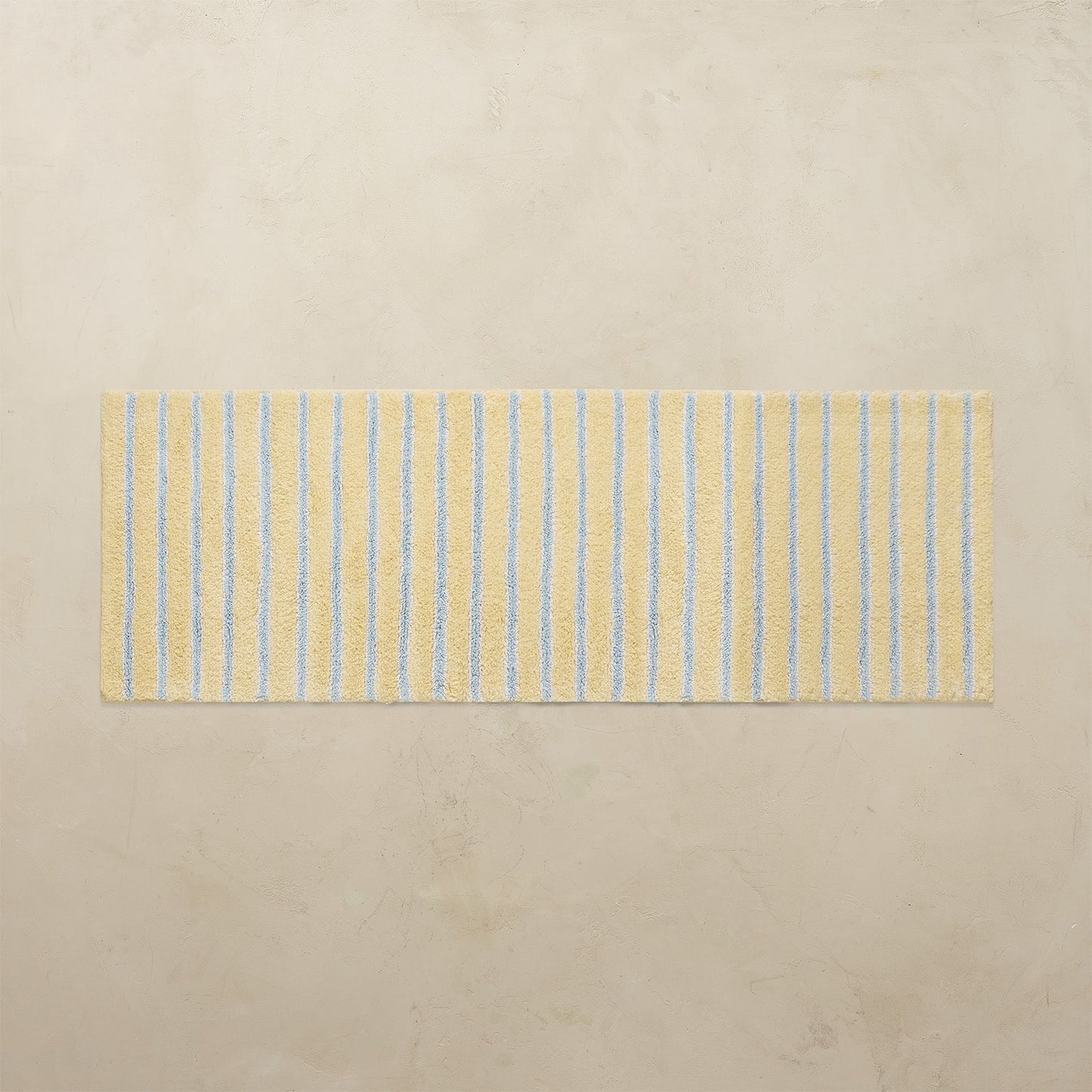 Striped yellow and blue bath rug on a beige floor