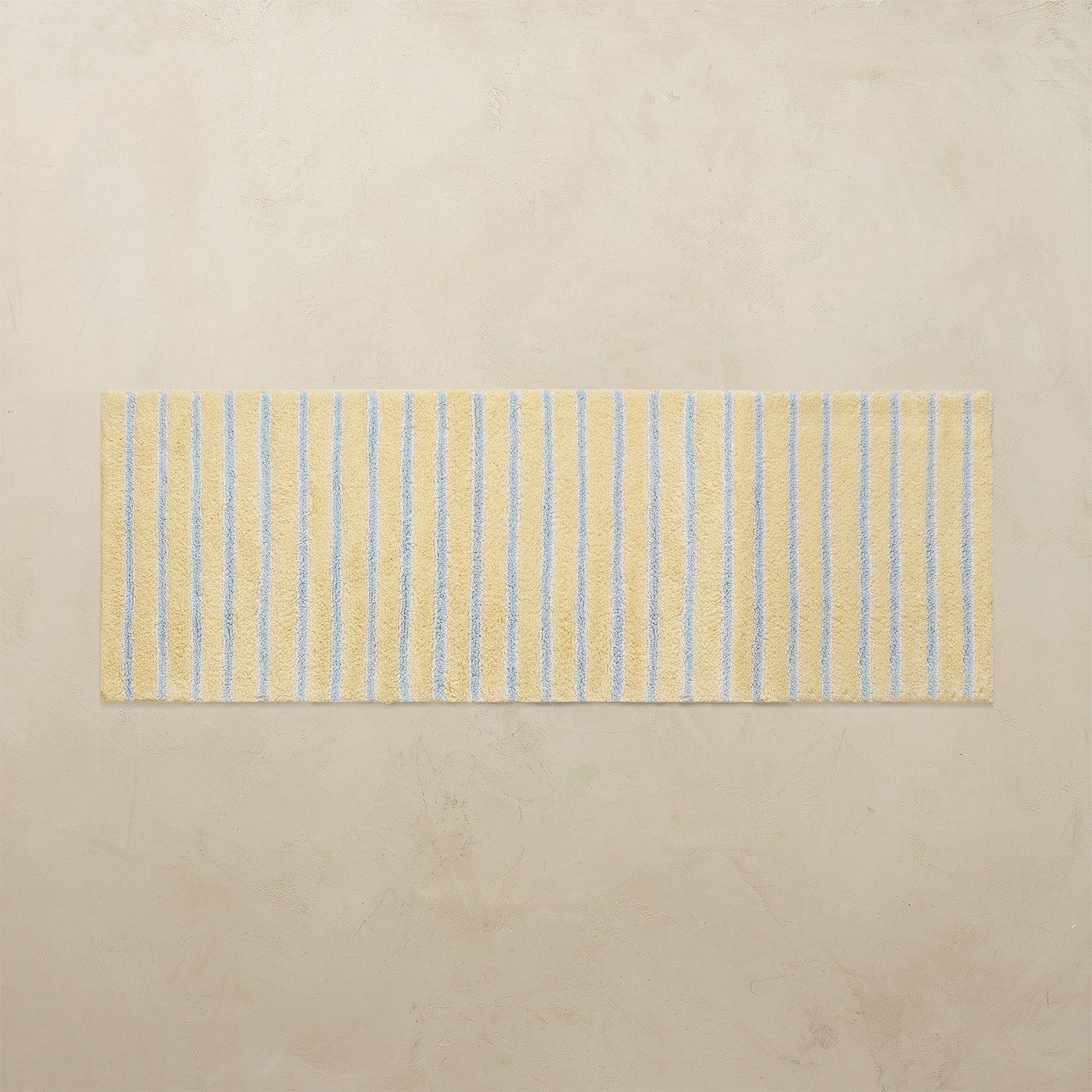 Striped yellow and blue bath rug on a beige floor