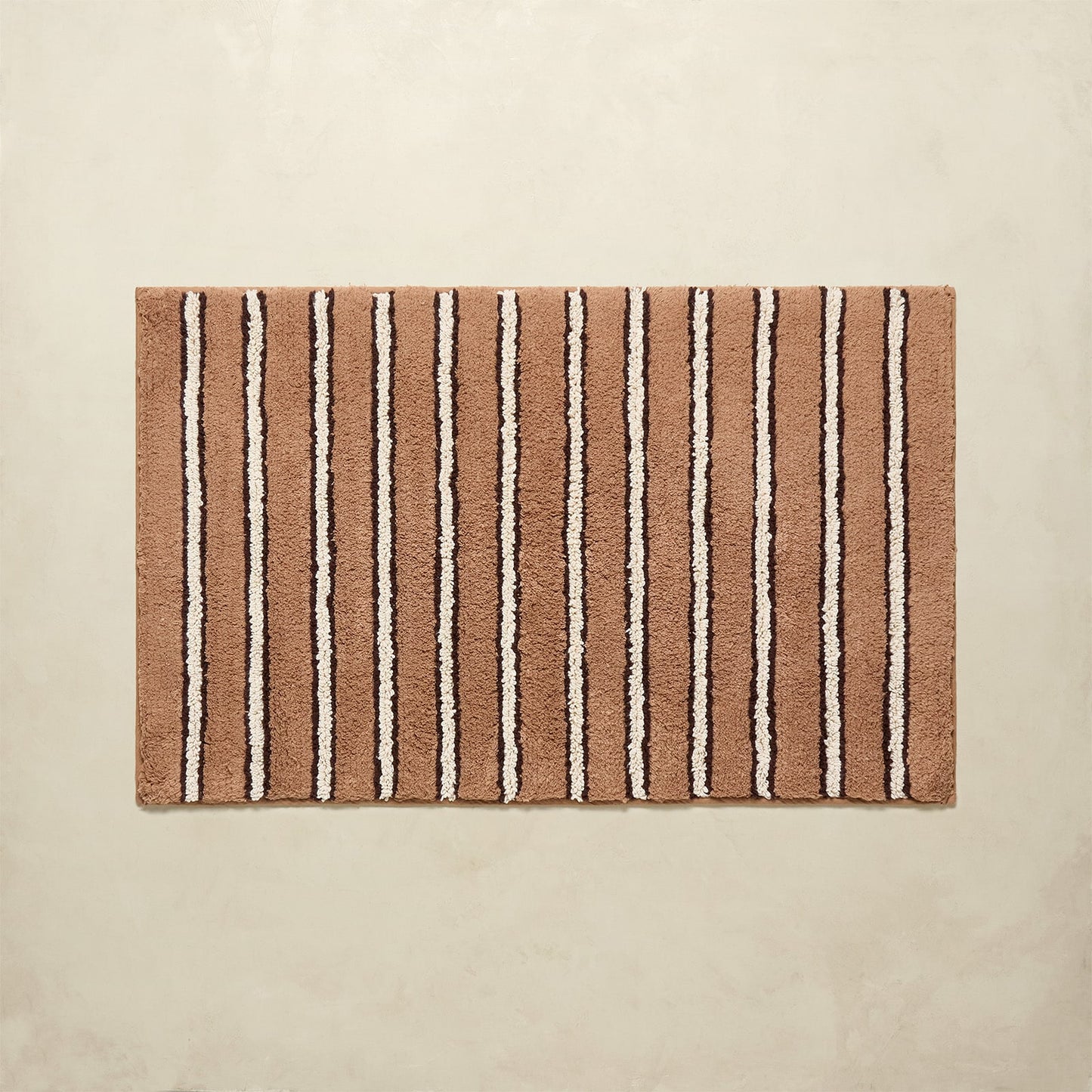 Striped bath mat with brown and beige stripes on a beige background