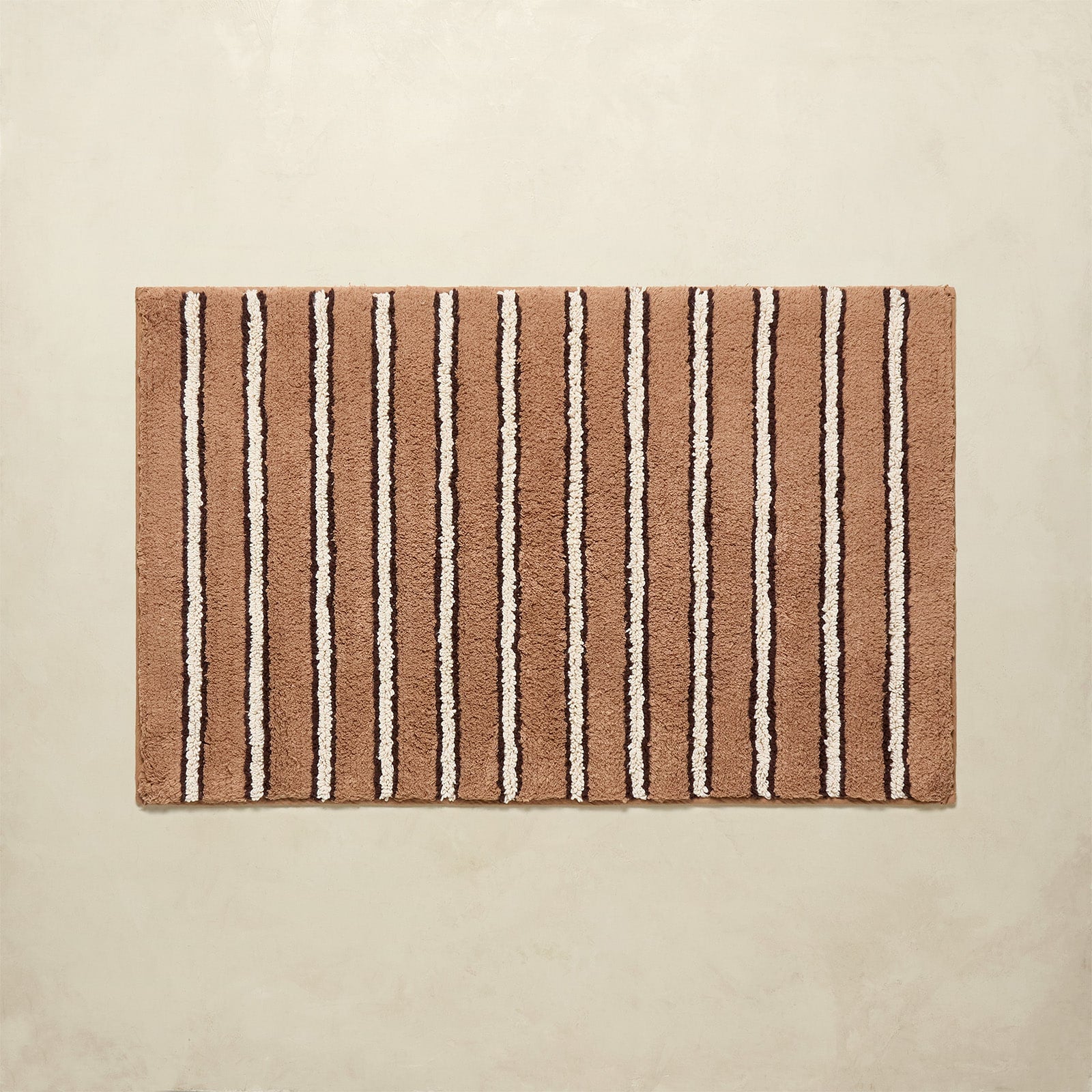Striped bath mat with brown and beige stripes on a beige background