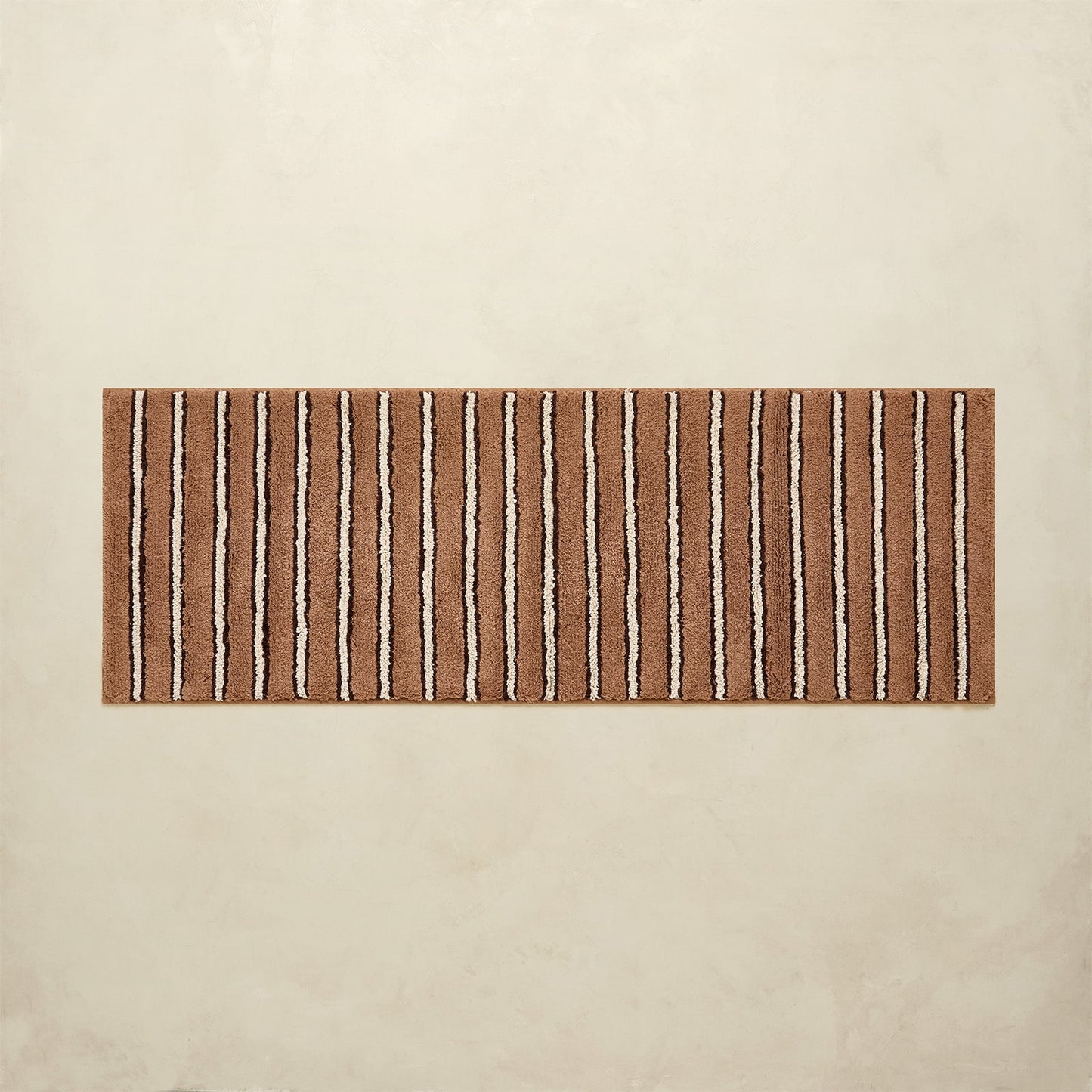 Striped brown and beige bath rug on a beige floor