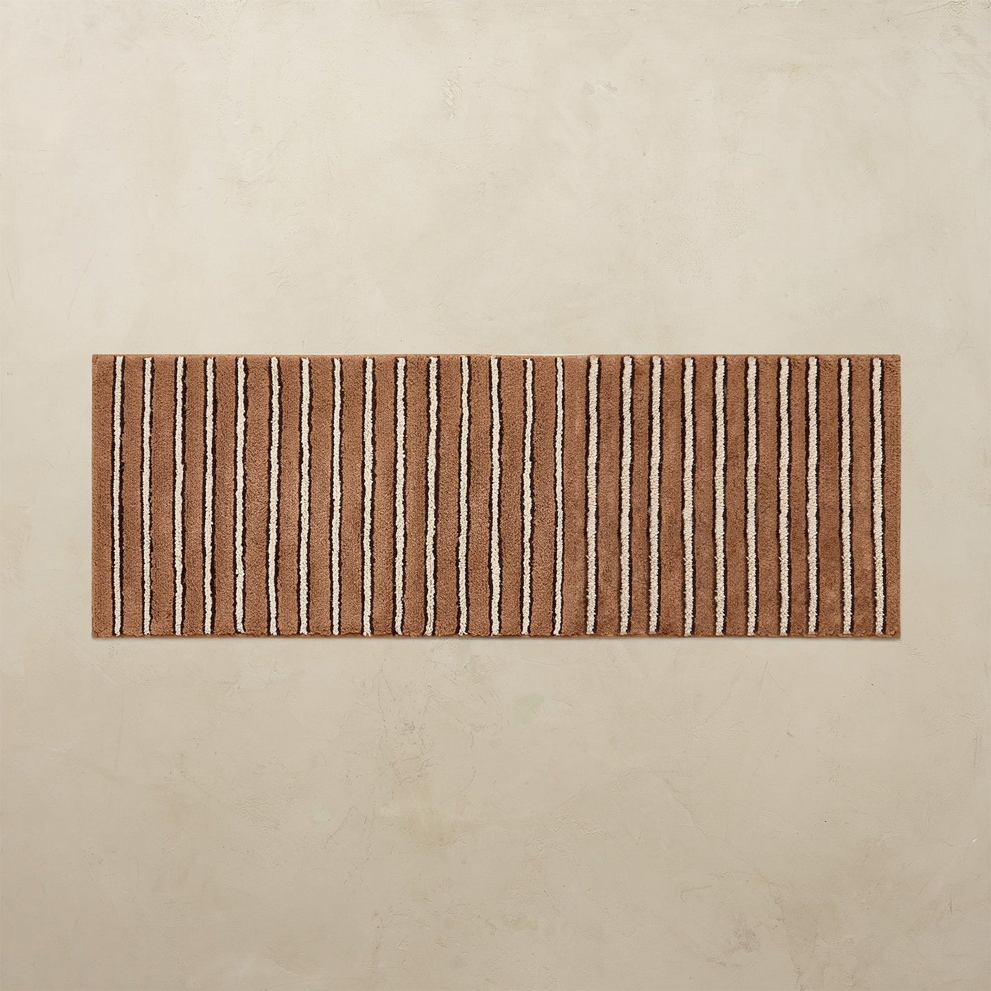 Striped bath mat with brown and beige pattern on a beige background