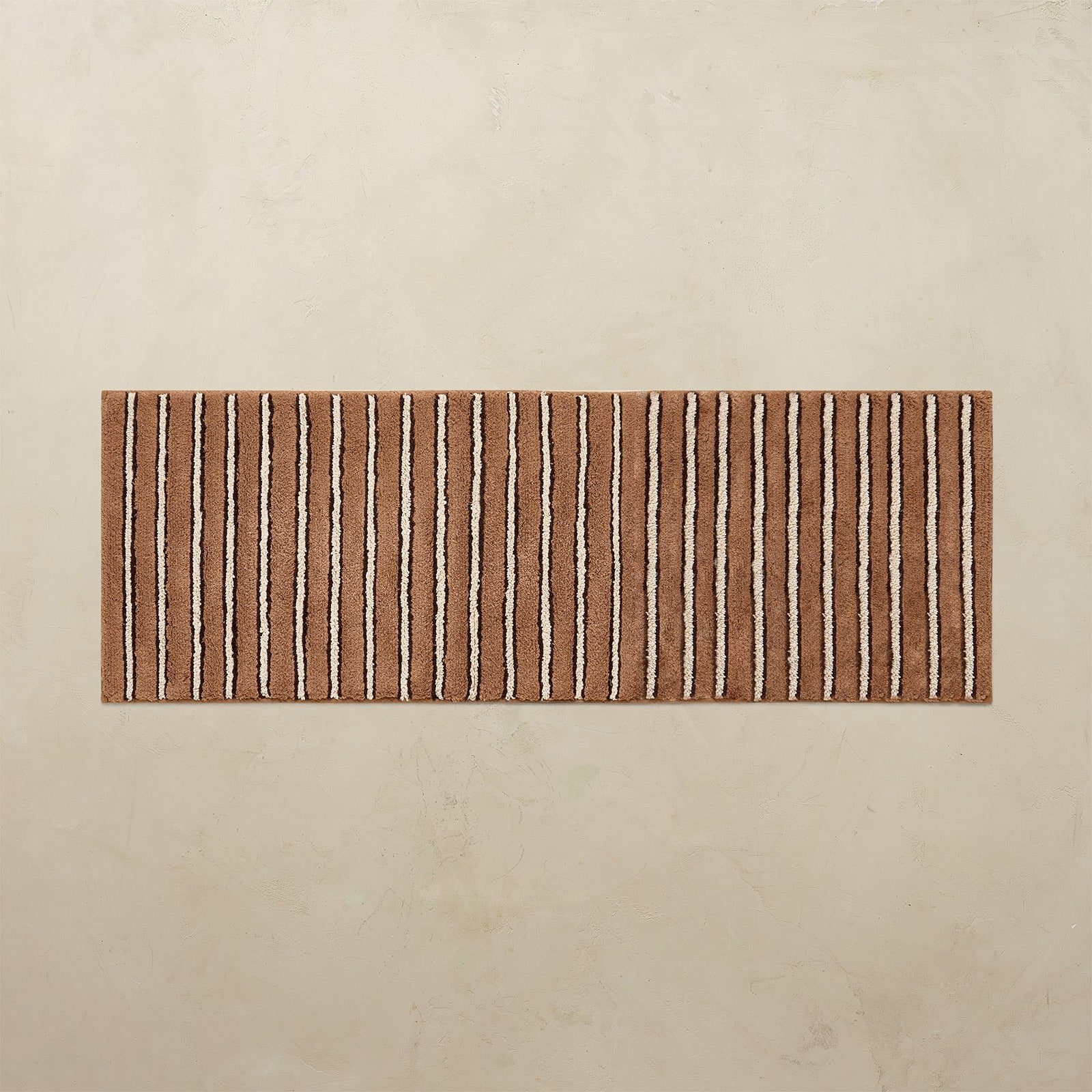 Striped bath mat with brown and beige pattern on a beige background