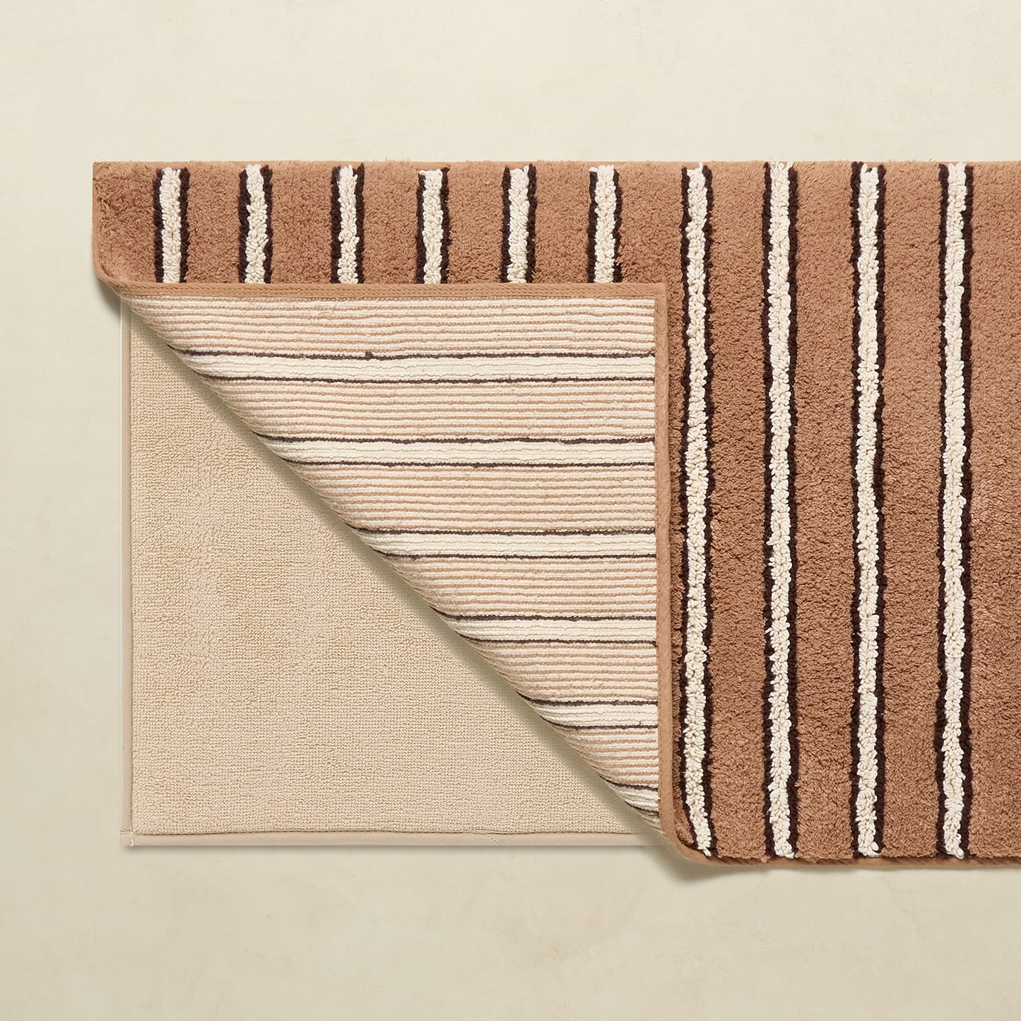 Two striped rugs, one brown and one beige, on a beige background.