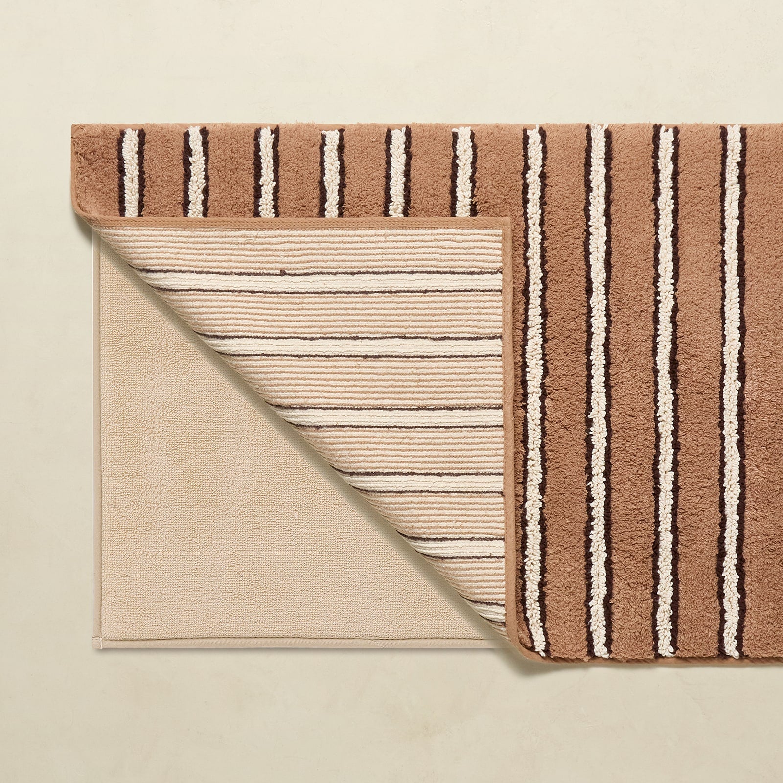 Two striped rugs, one brown and one beige, on a beige background.