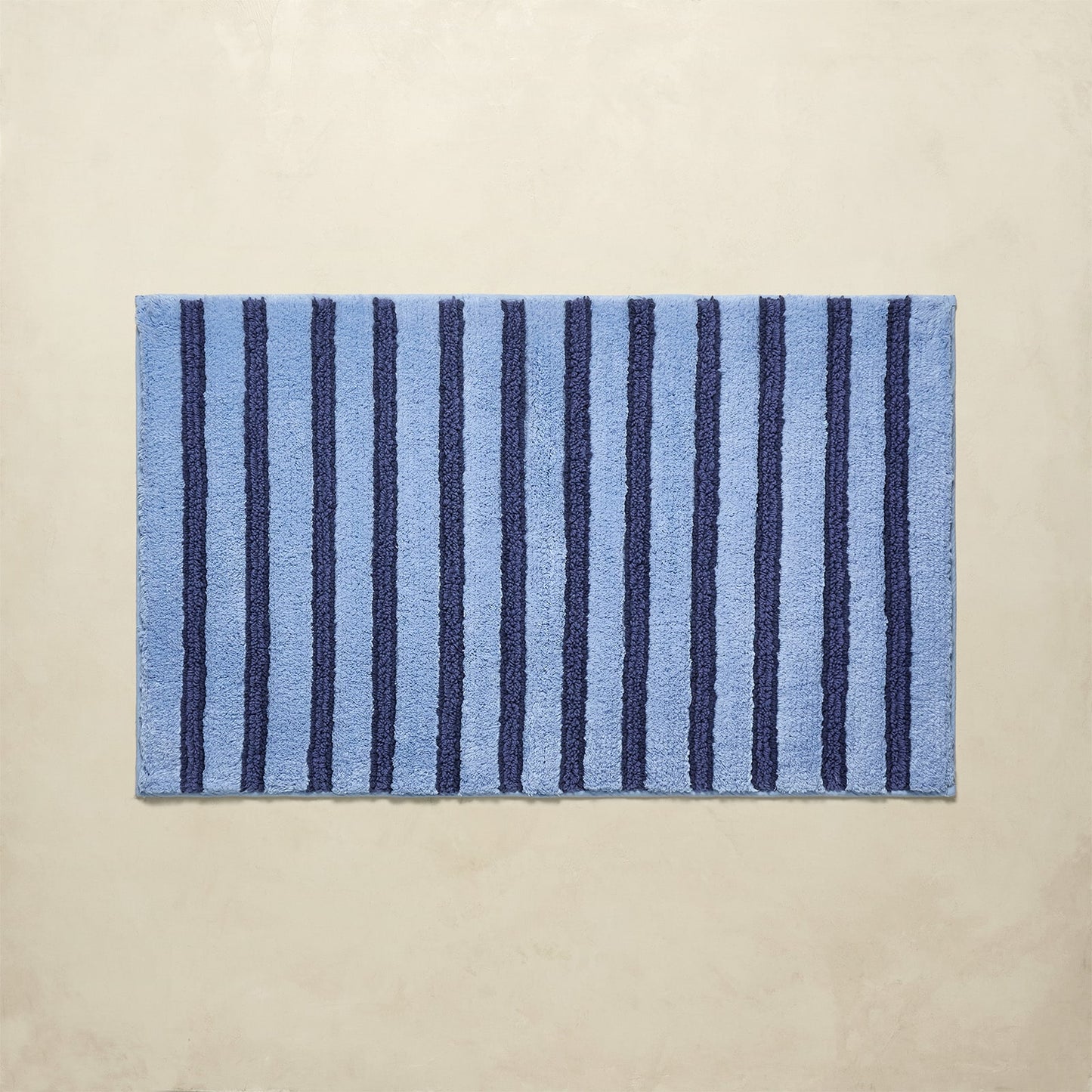 Striped blue bath rug with vertical lines on a beige background