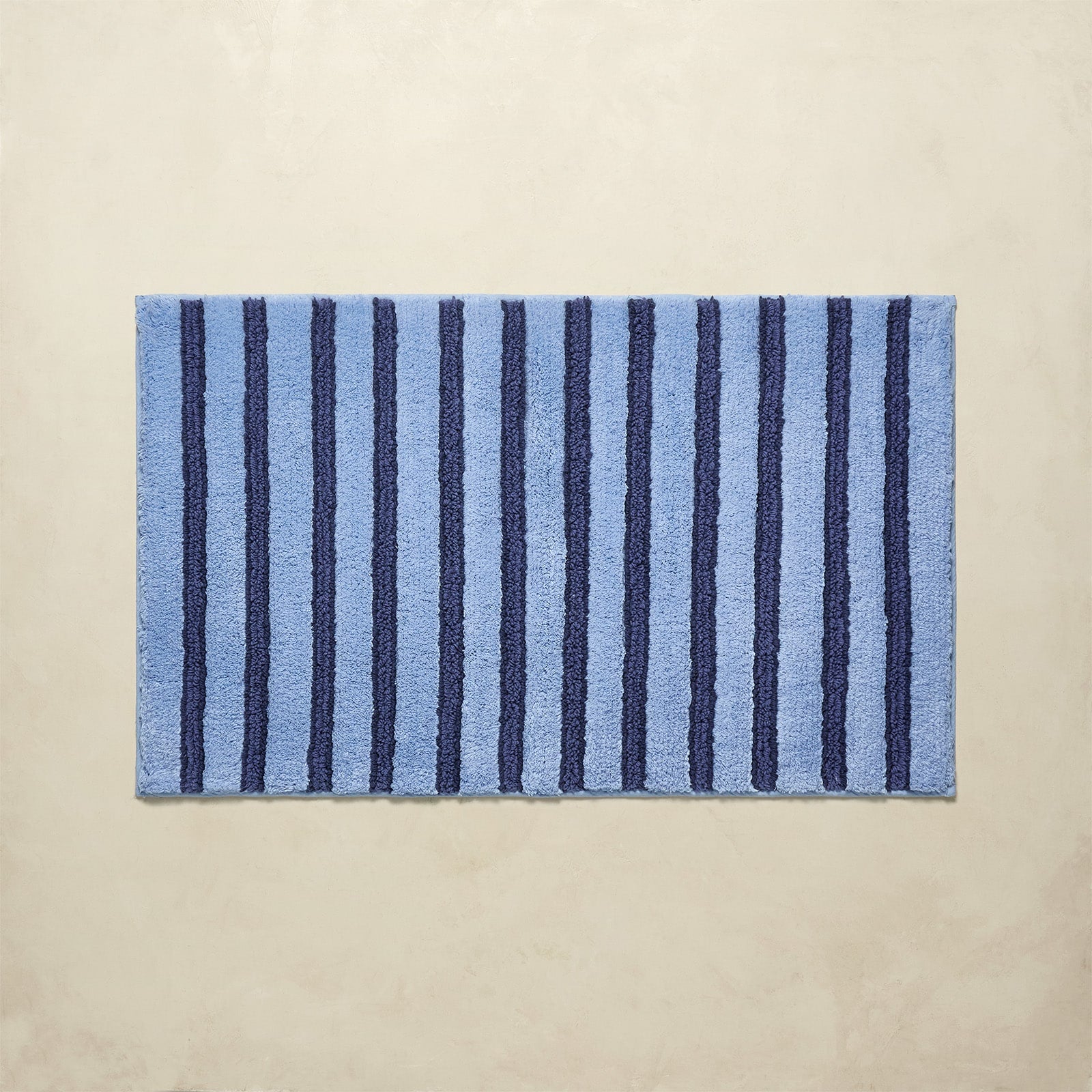 Striped blue bath rug with vertical lines on a beige background