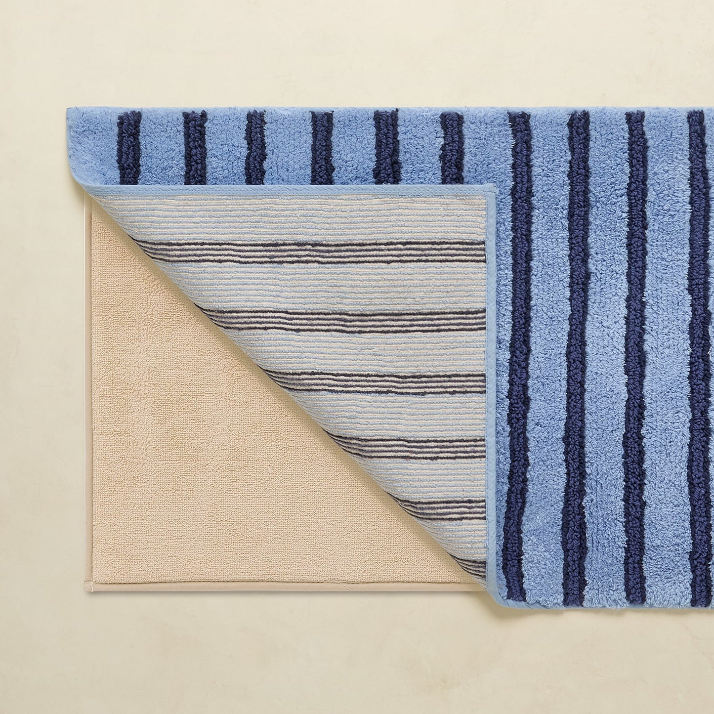 Blue striped rug with beige backing on a beige background