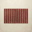Rectangular bath mat with red and white vertical stripes on a beige background