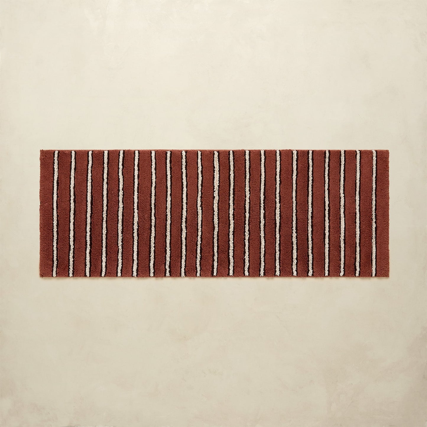 Striped red and white bath rug on a beige background
