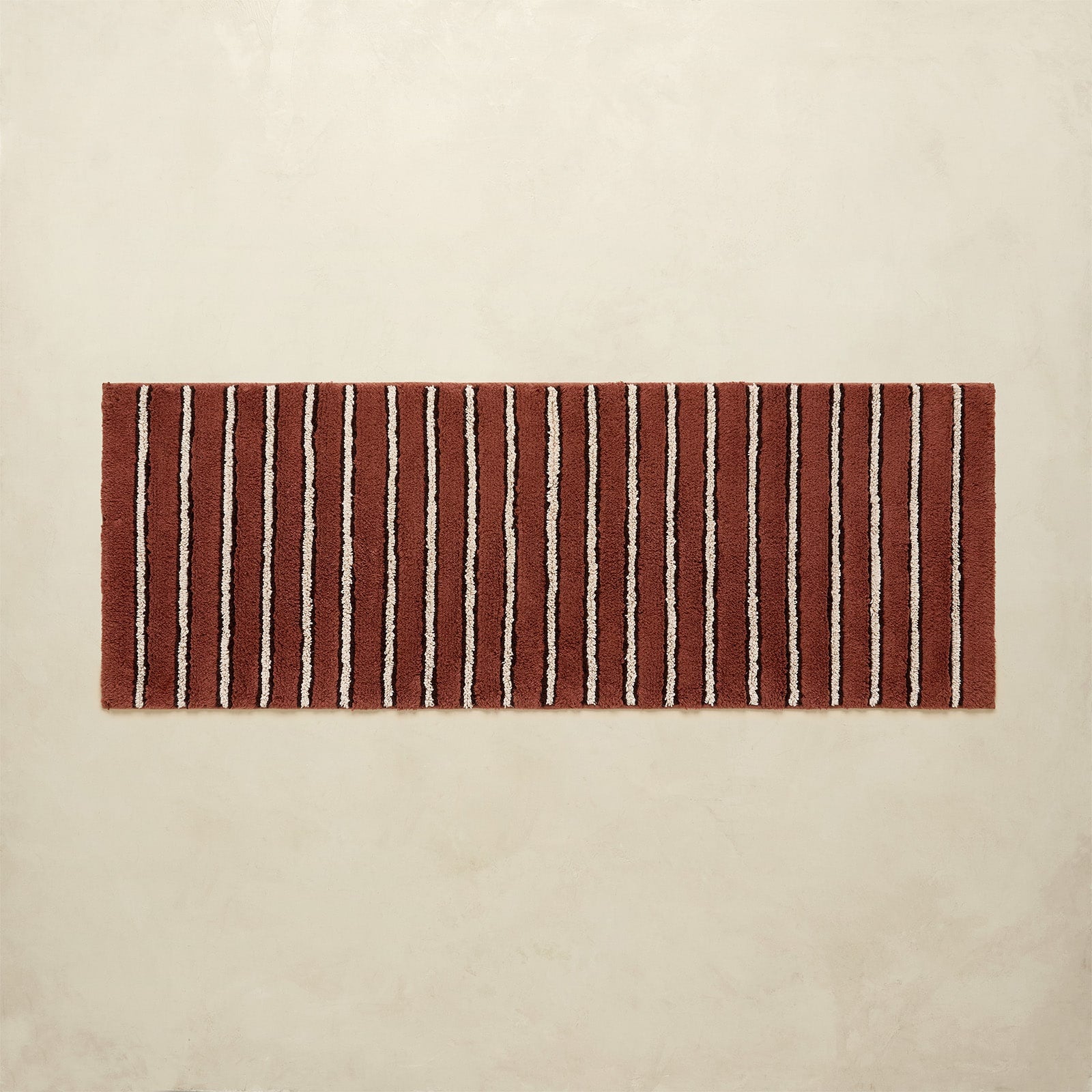 Striped red and white bath rug on a beige background