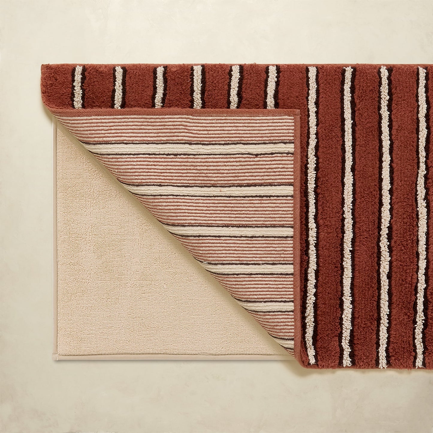 Striped bath rug with brown and beige colors on a neutral background
