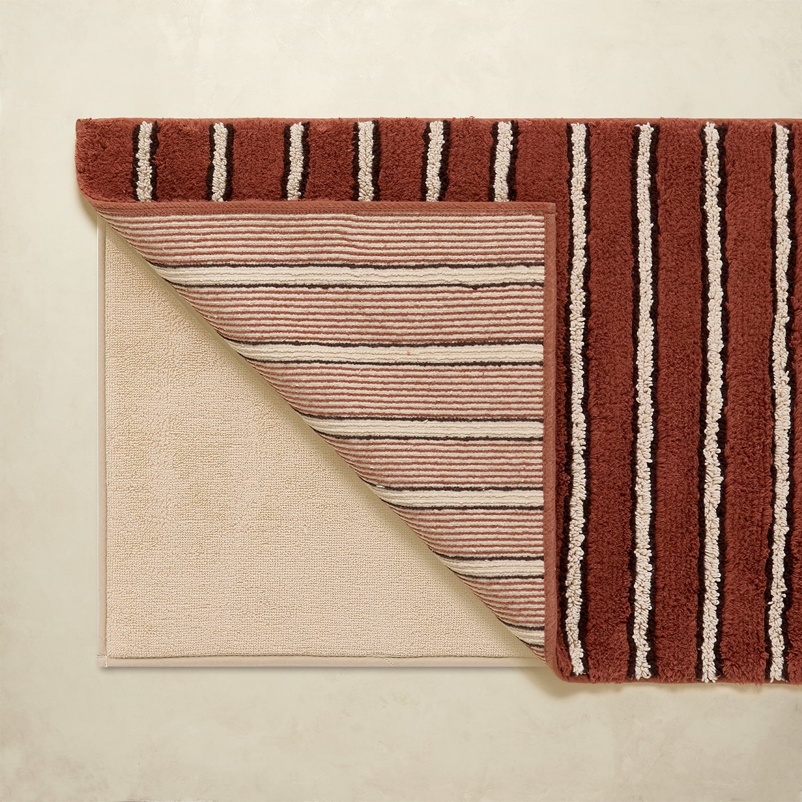 Striped bath rug with brown and beige colors on a neutral background