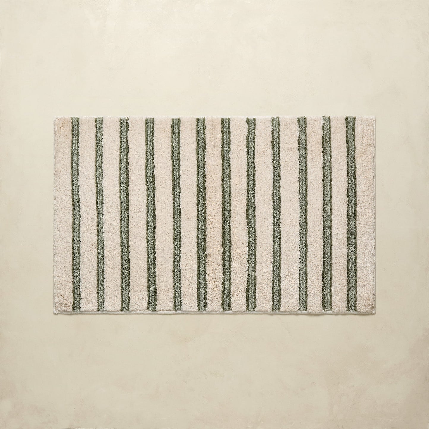 Striped bath rug with green and beige stripes on a beige background