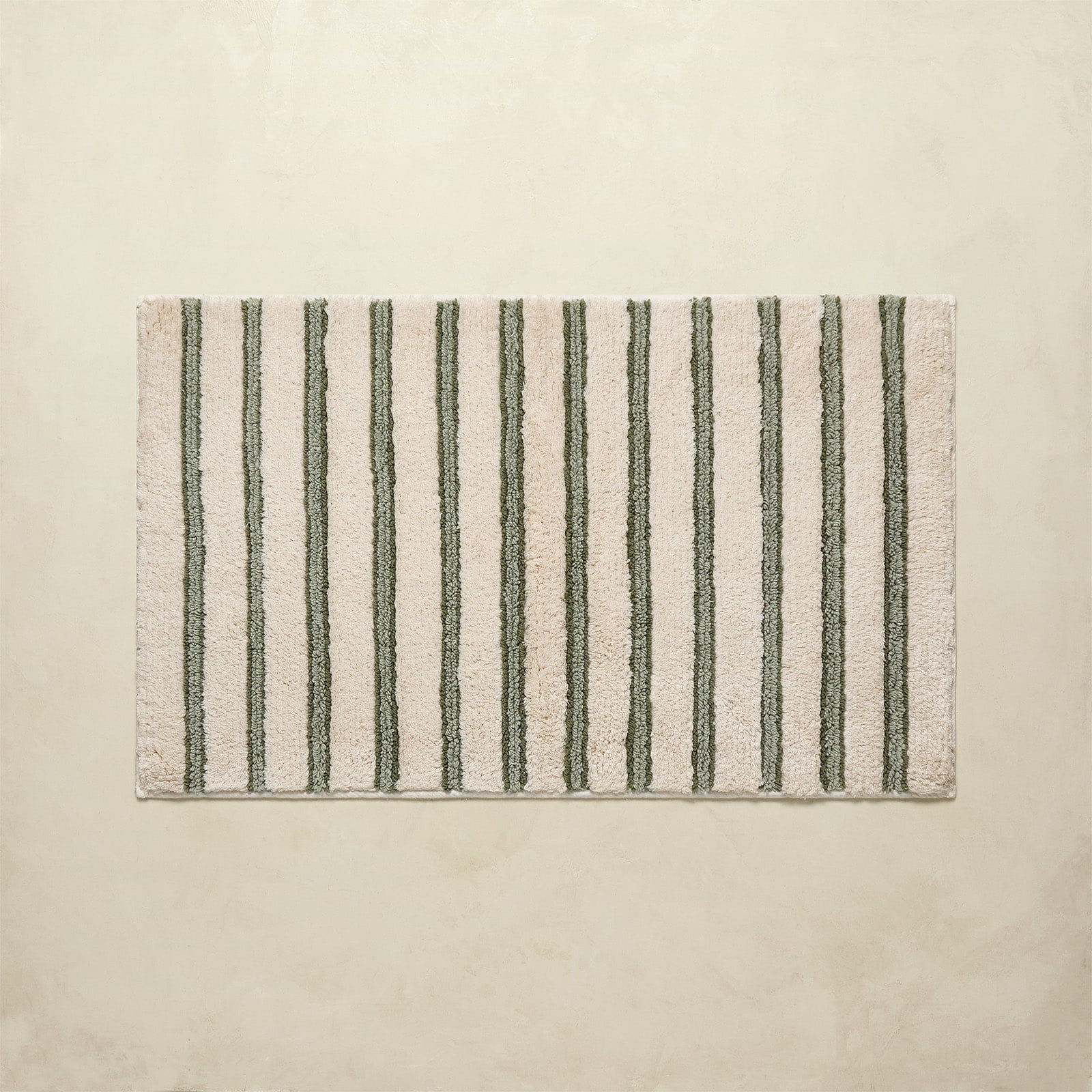 Striped bath rug with green and beige stripes on a beige background