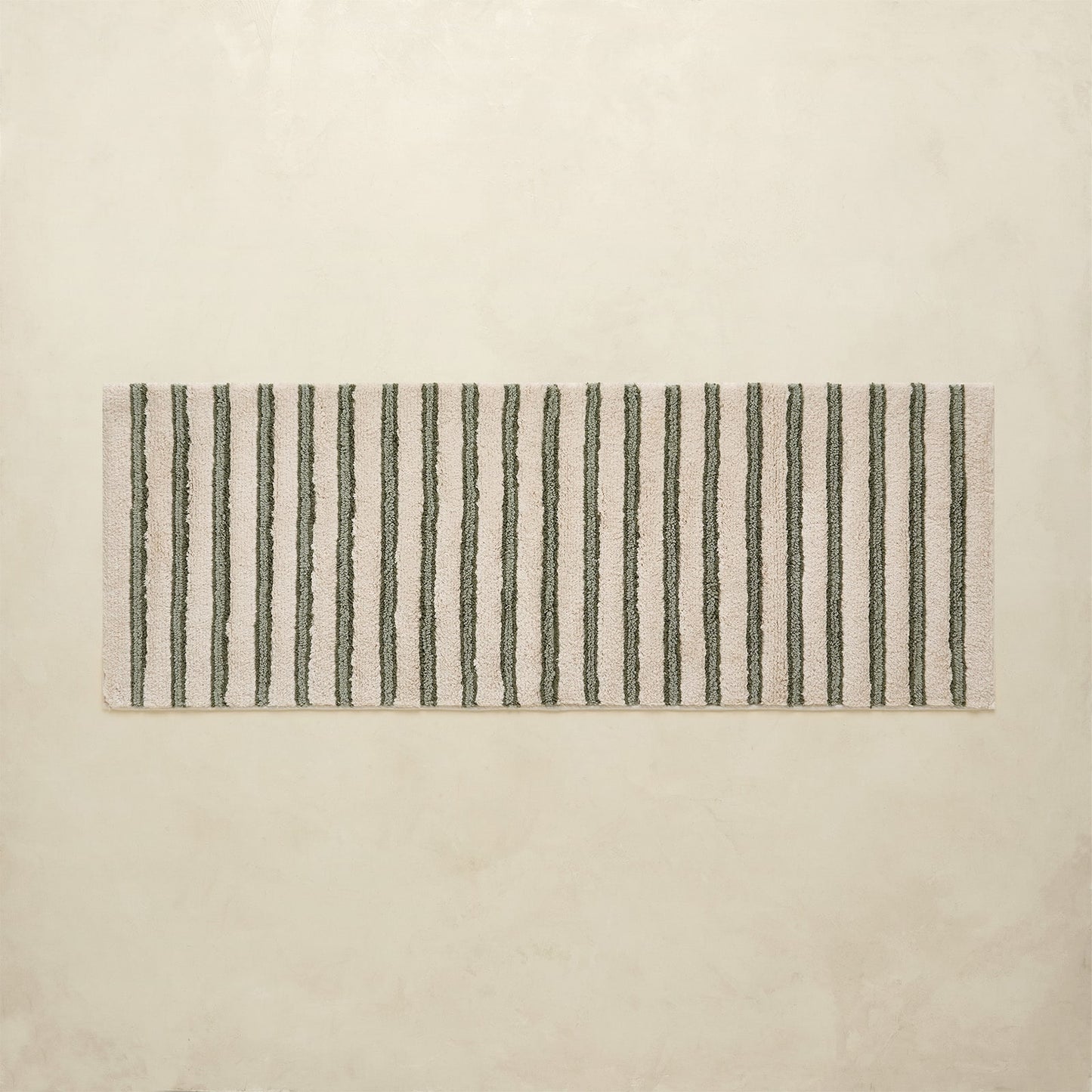 Rectangular bath rug with black vertical stripes on a beige background