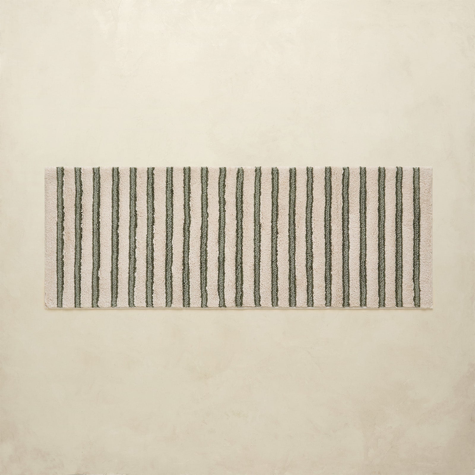 Rectangular bath rug with black vertical stripes on a beige background