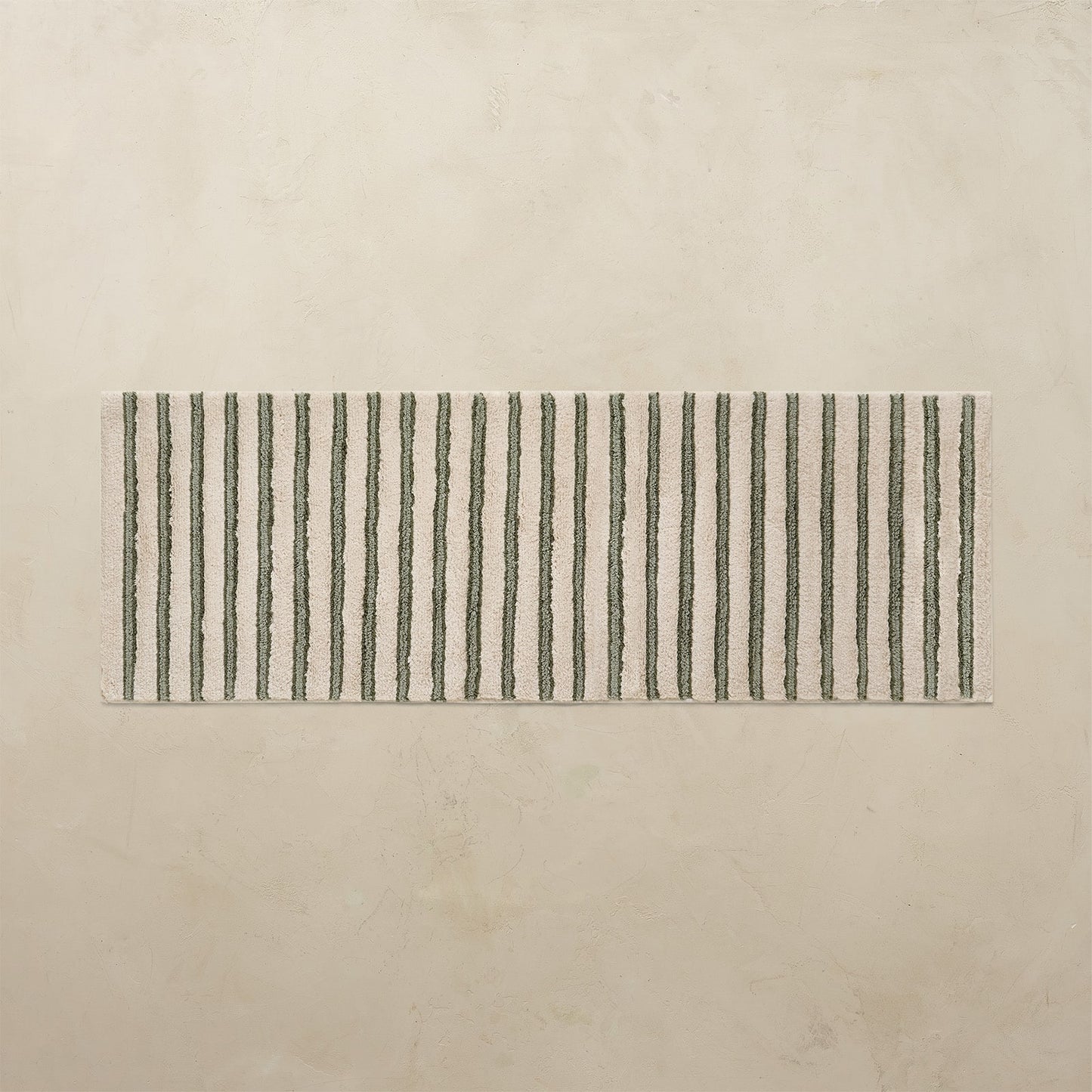 Rectangular bath rug with green vertical stripes on a beige background