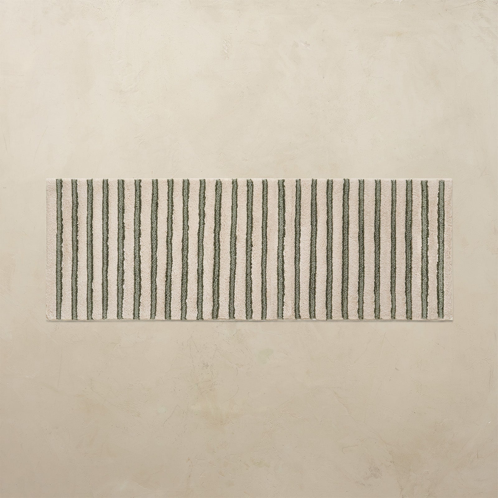 Rectangular bath rug with green vertical stripes on a beige background