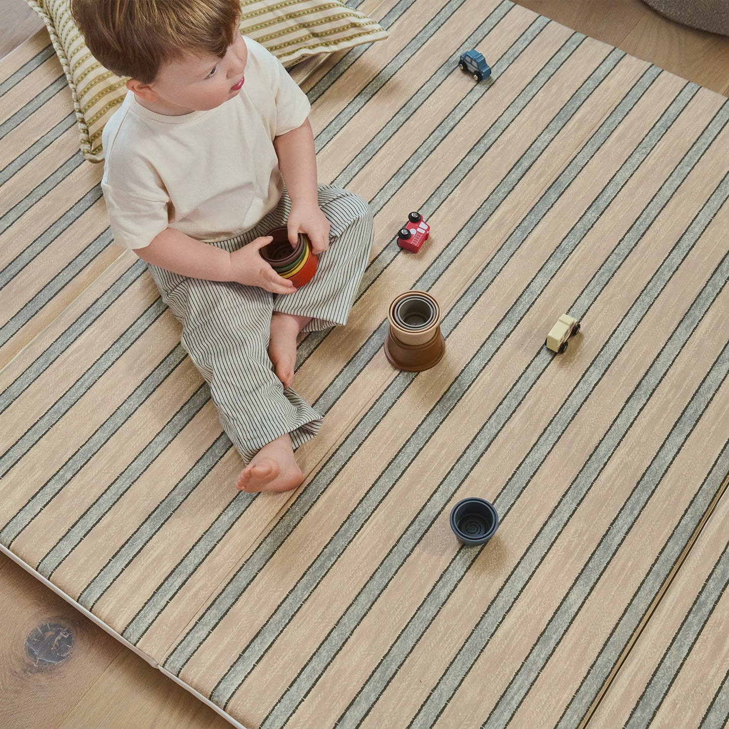 Child playing with toys on a striped tumbling mat