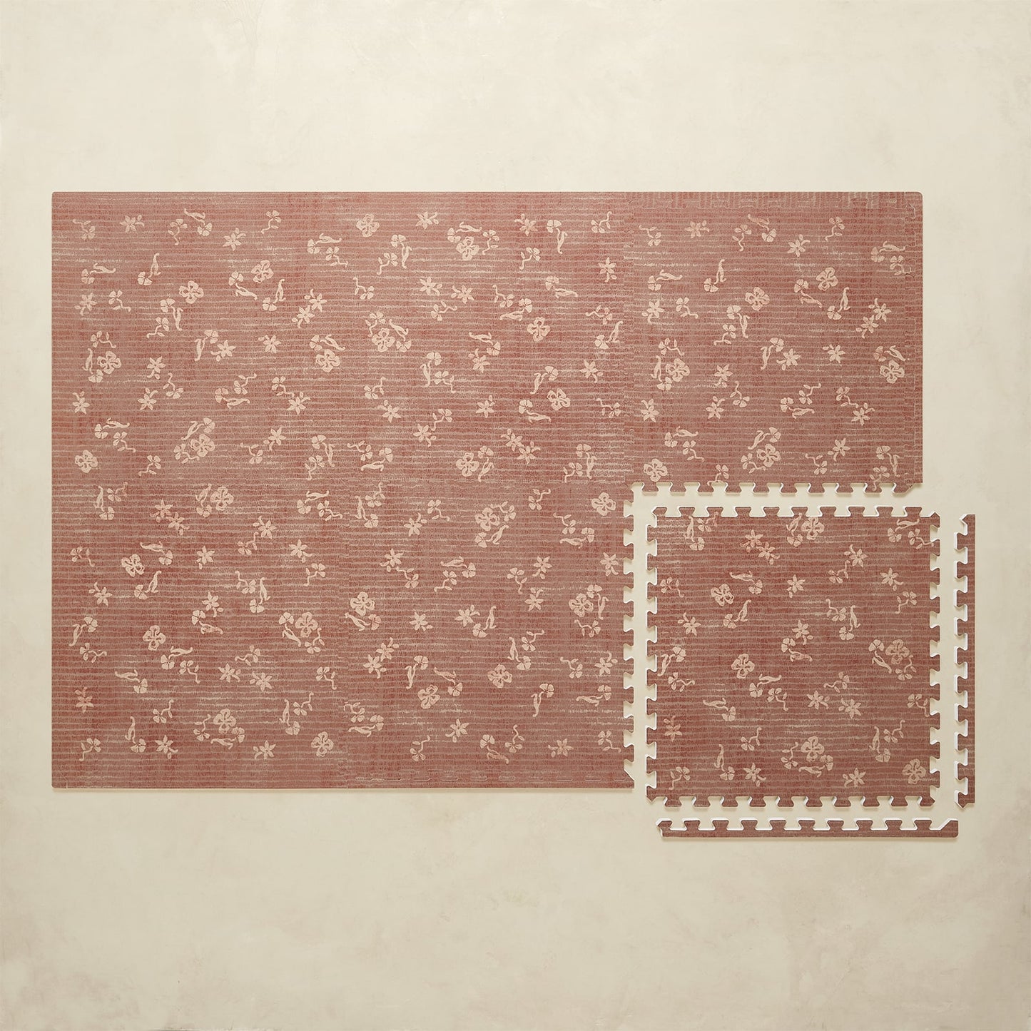 Floral-patterned play mat with interlocking foam tiles on a beige background