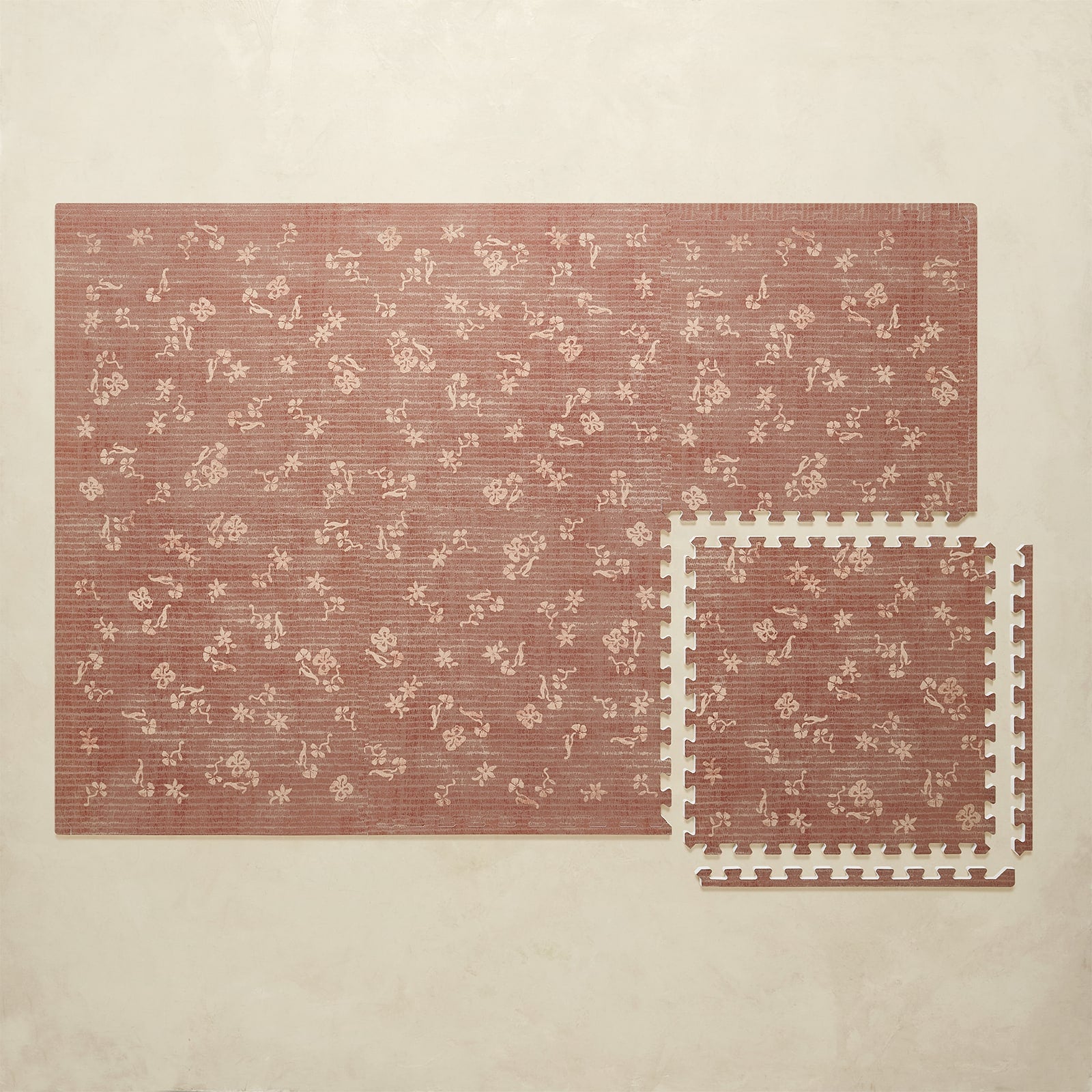 Floral-patterned play mat with interlocking foam tiles on a beige background