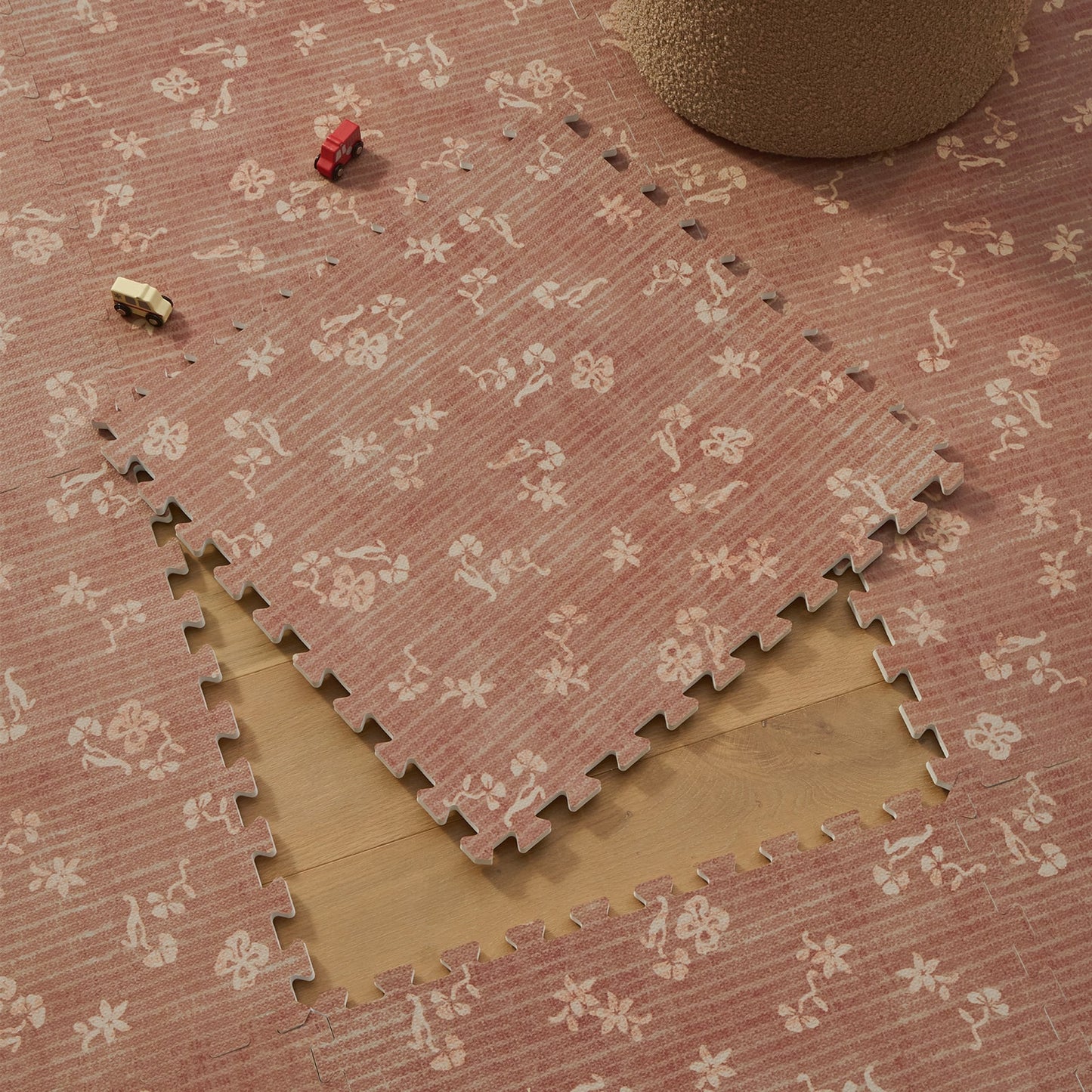 Brown floral-patterned interlocking foam mats on a wooden floor.