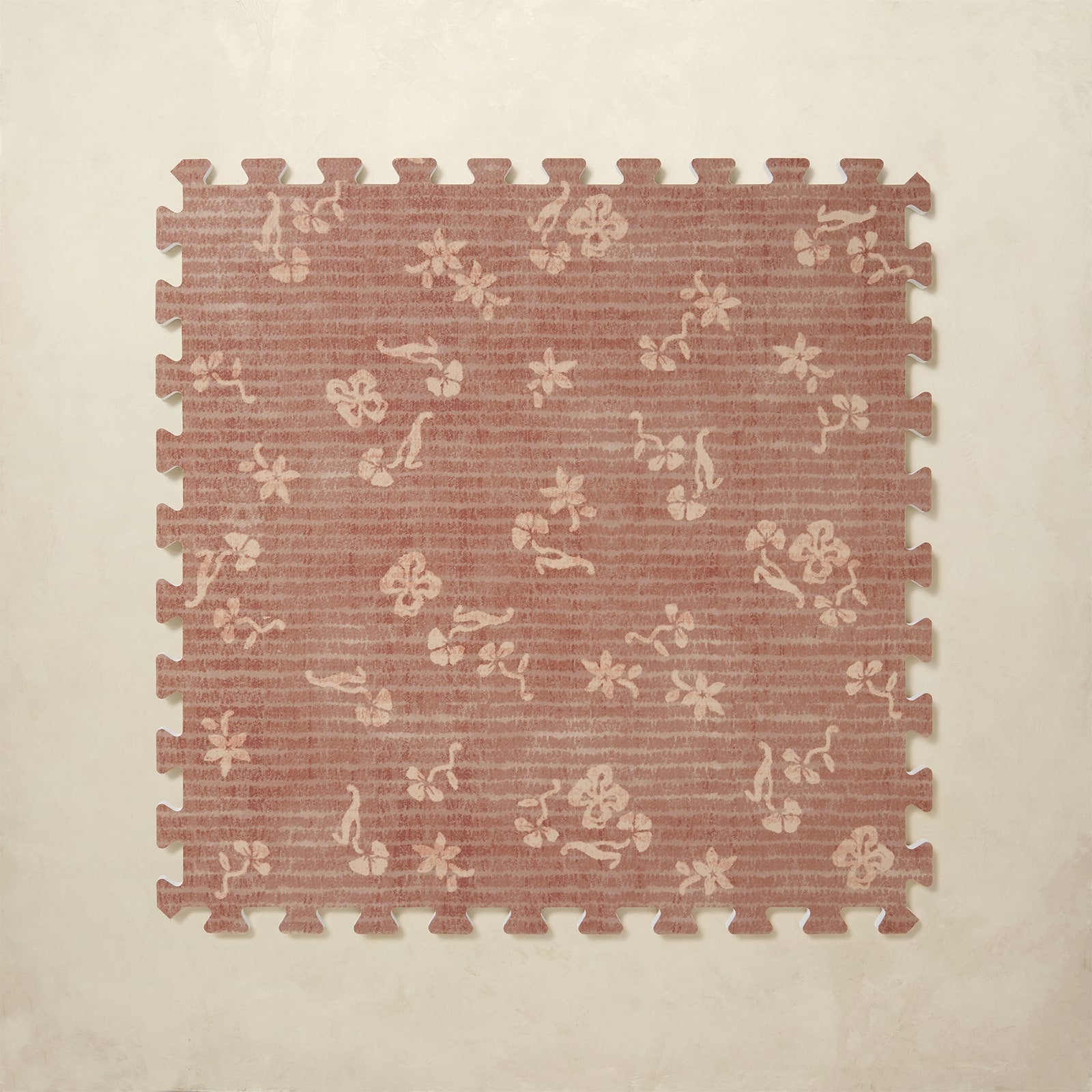 Floral patterned foam puzzle mat on a beige background