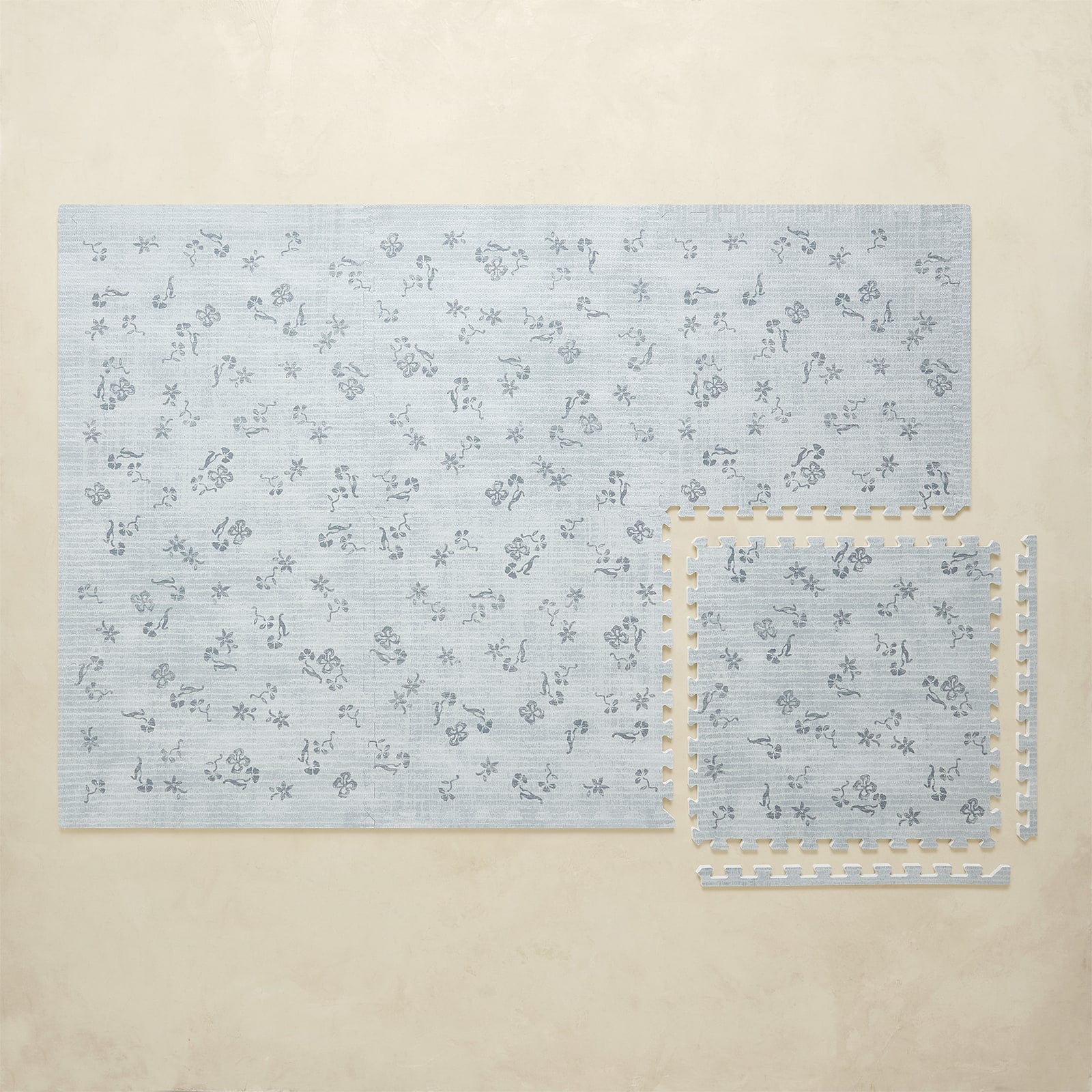 Blue floral-patterned play mat on a beige surface