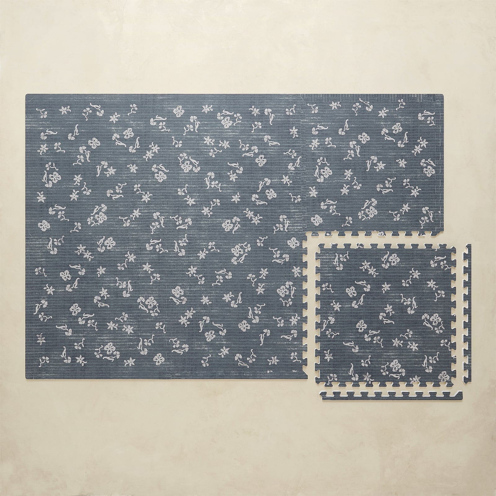 Blue floral-patterned play mat on a beige background