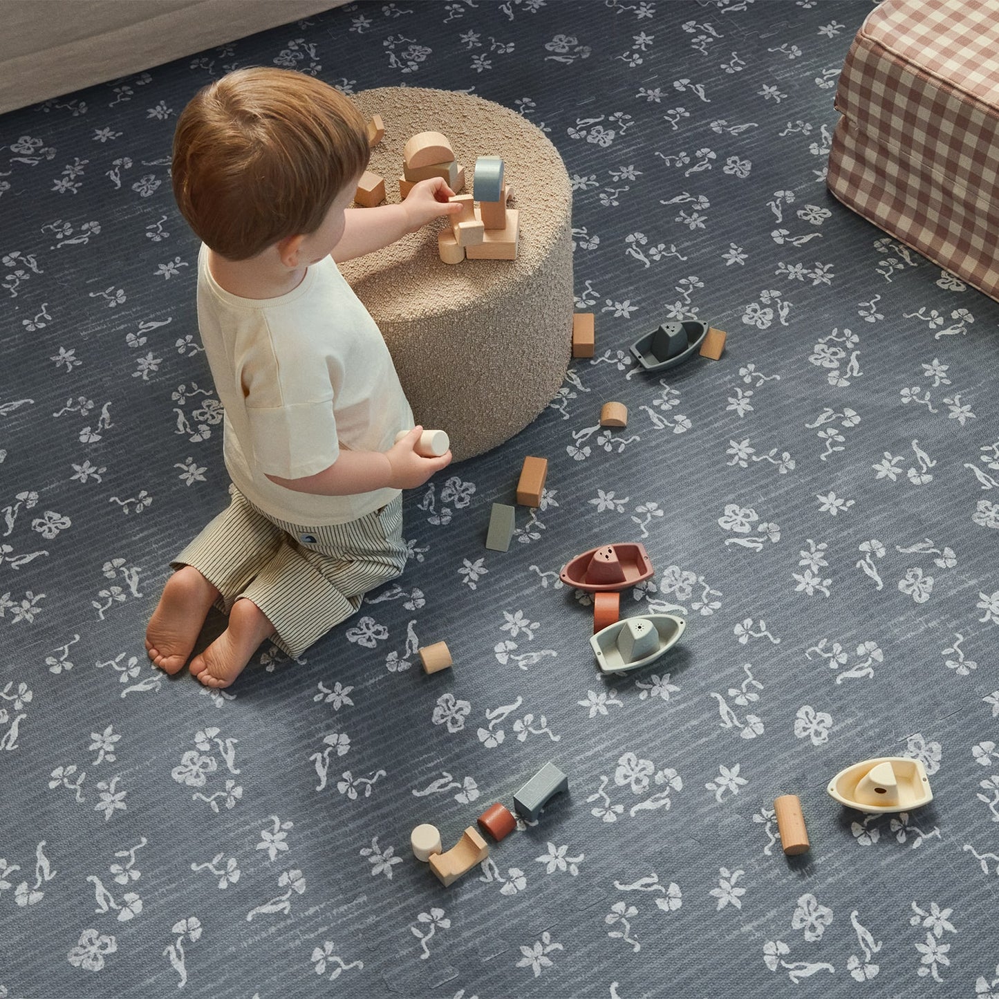 Child playing with toys on a patterned blue play mat