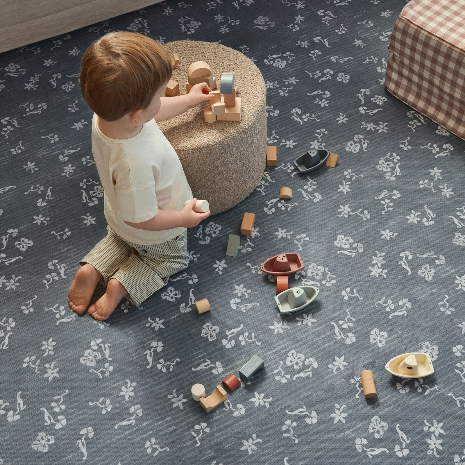 Child playing with toys on a patterned blue play mat