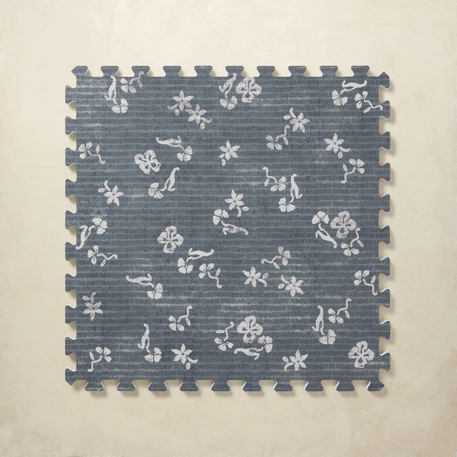 Blue floral patterned interlocking foam tile on a beige background