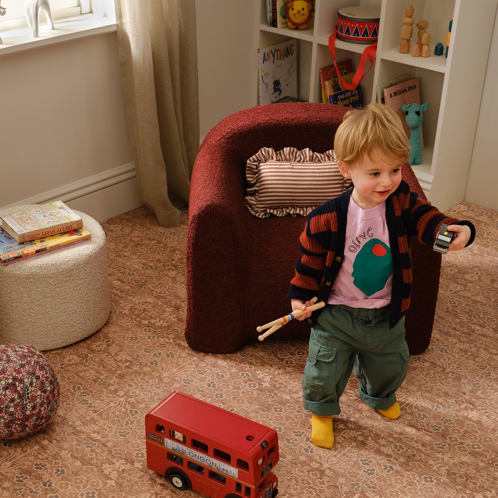 Child playing with toys in a room with a red chair and books.