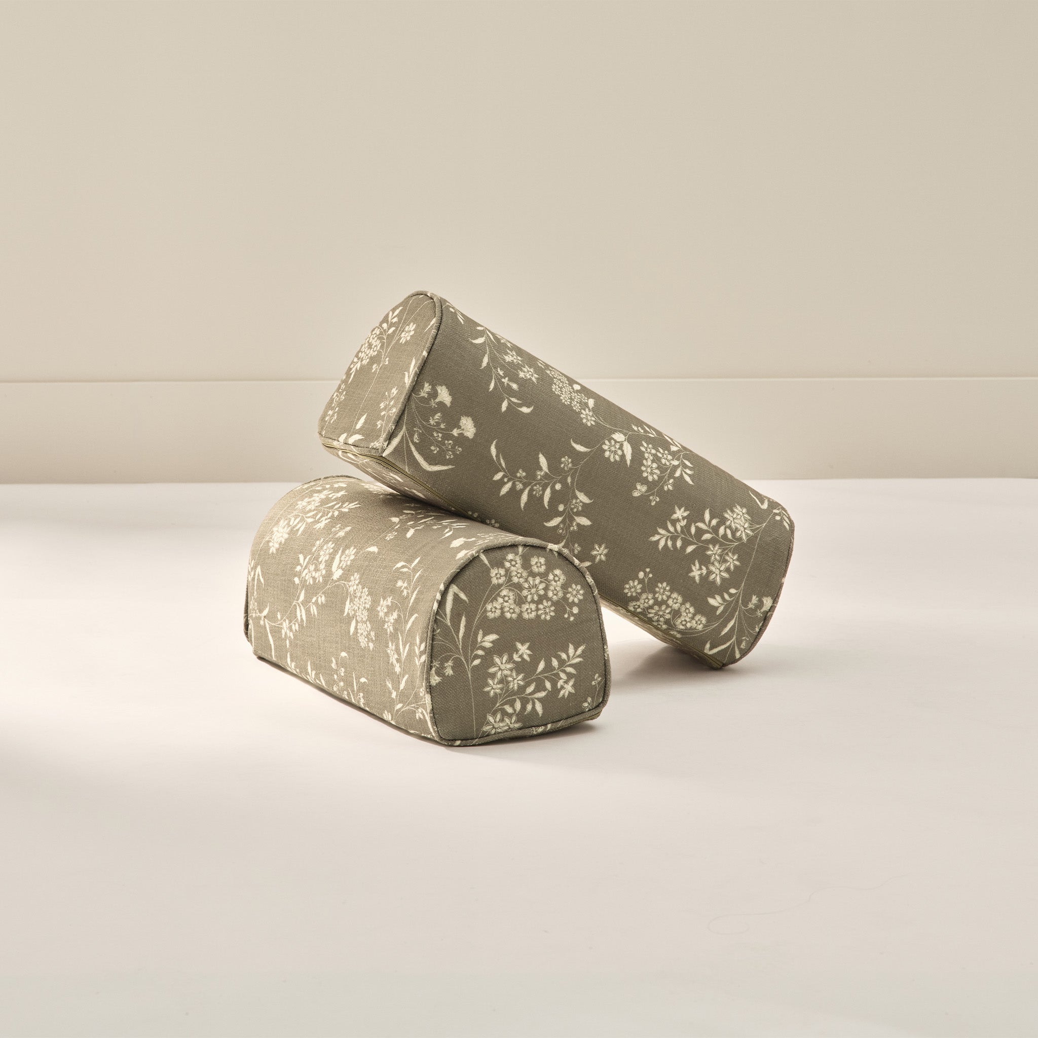 Two floral patterned arch cylindrical armrest pillows from House of Noa in cream and jade