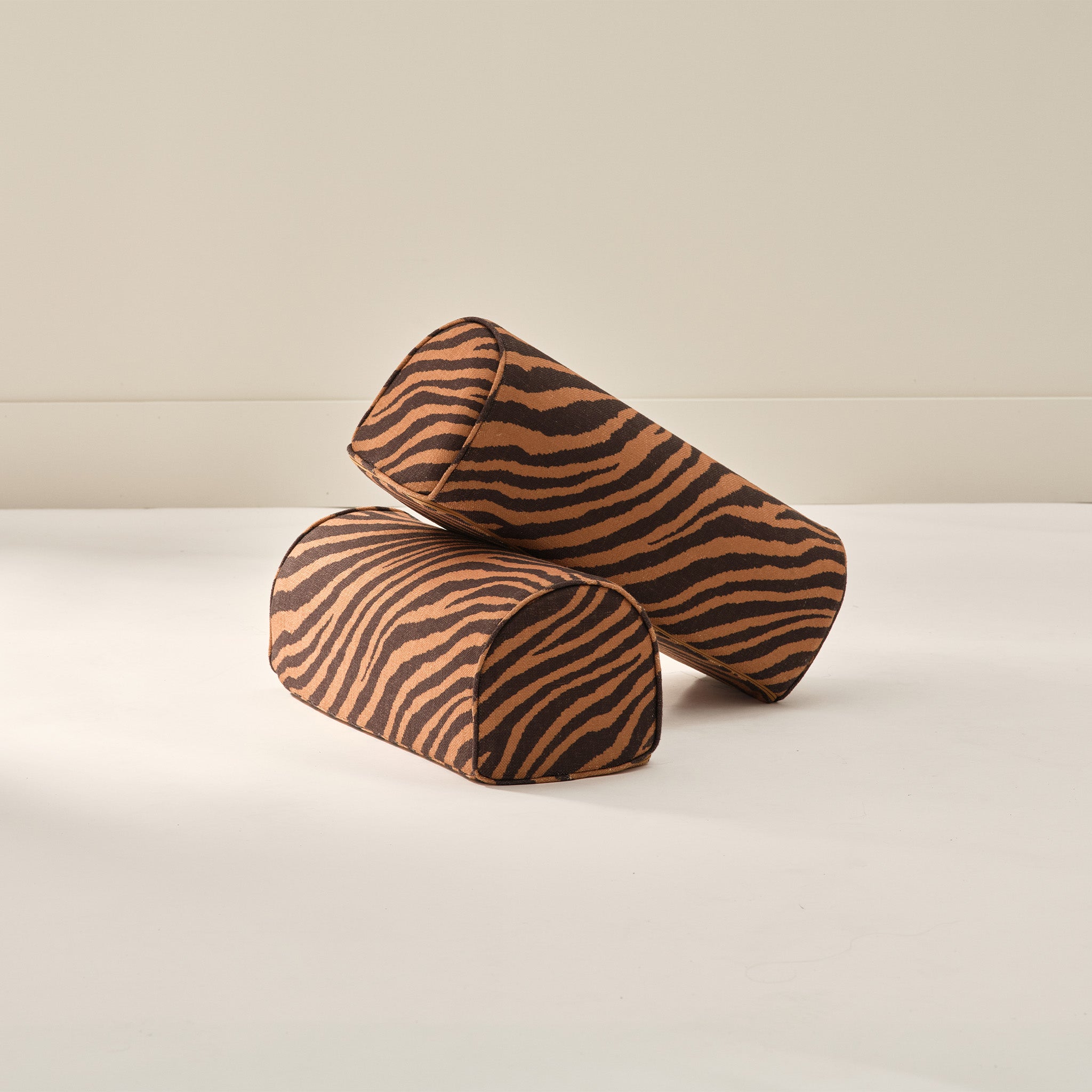 Two striped arch cylindrical armrest pillows from House of Noa in amber and sable
