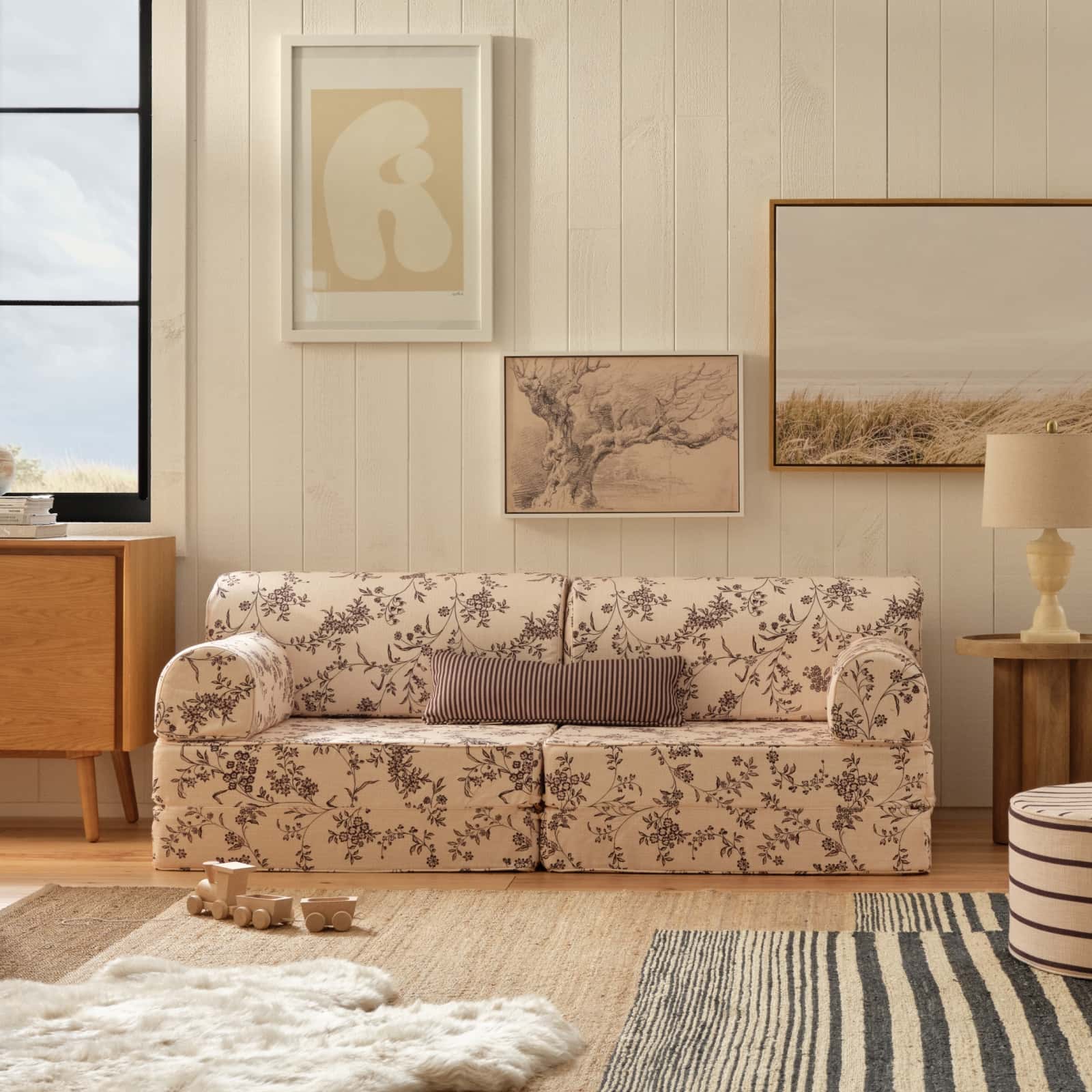 Living room with floral-patterned sofa, wooden side table, and framed artwork on the wall.