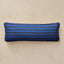 A rectangular navy lumbar pillow with horizontal blue stripes, shown against a neutral beige textured background.